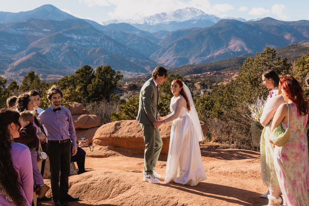 A wedding ceremony takes place on red rocks overlooking mountain peaks at Garden of the Gods in Colorado Springs.