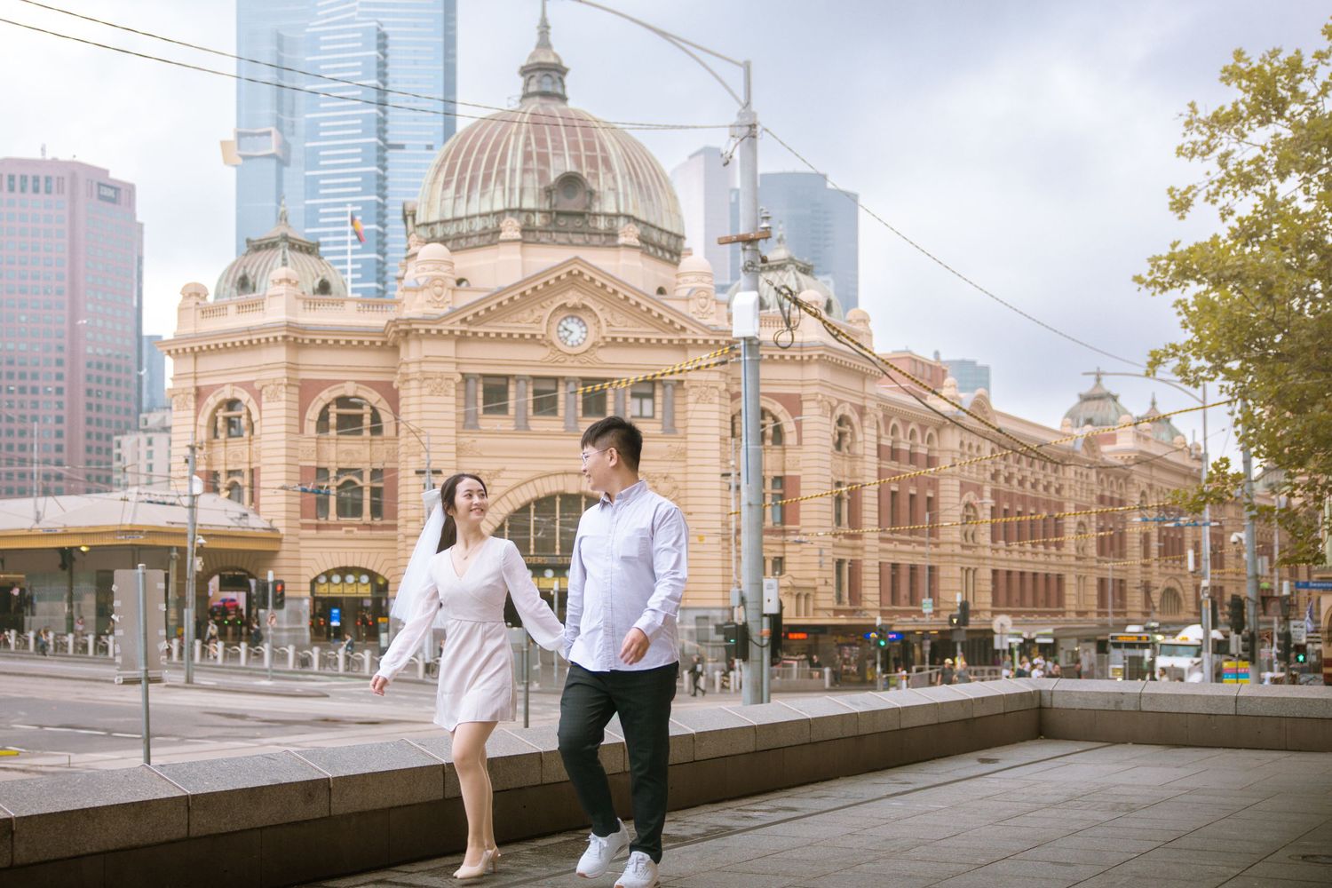 A couple poses playfully outside the historic Flinders Street Station in Melbourne.