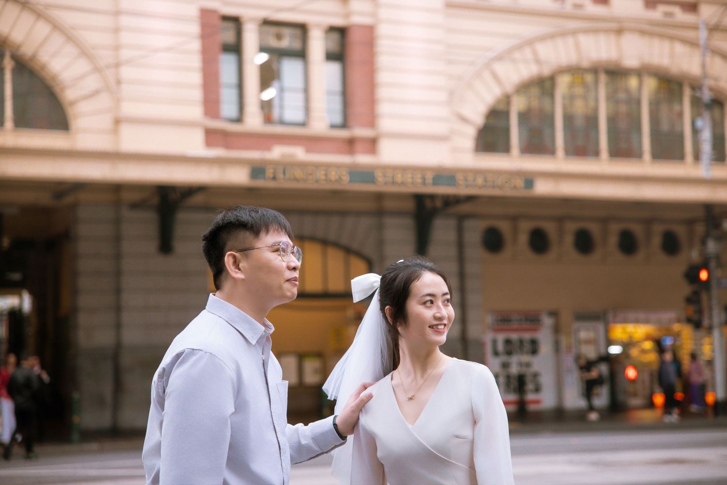 A happy couple sharing a light moment outside Melbourne's landmark Flinders Street Station.