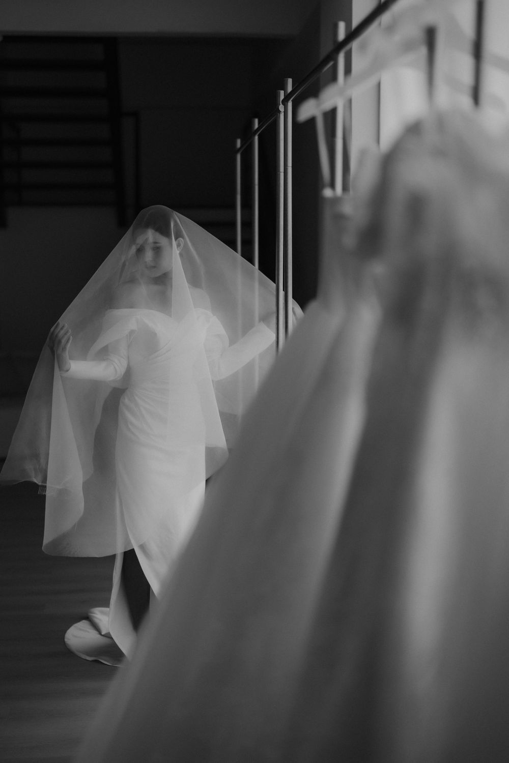 A dreamy black and white bridal portrait with flowing veil and dramatic lighting in a hallway.