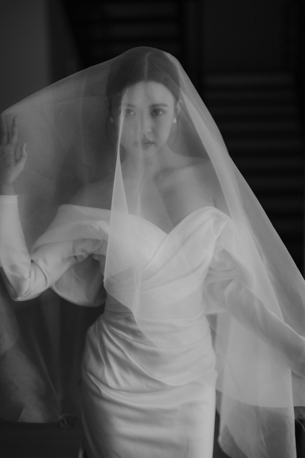 Ethereal bridal portrait with flowing veil and structured white gown.