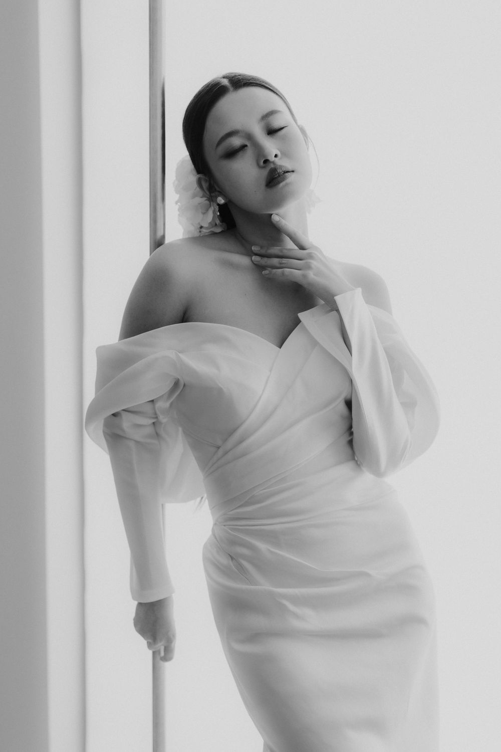 Elegant black and white portrait in draped white off-shoulder dress.