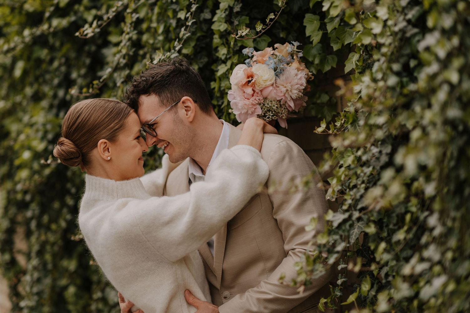 Intimate wedding portraits showing tender moments between a couple against an ivy-covered wall.