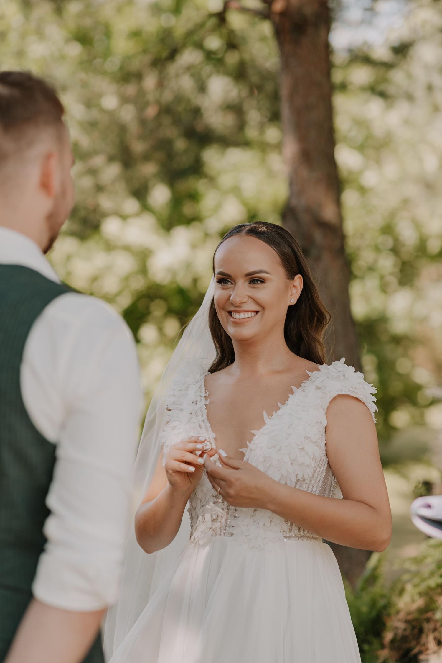 Bride in white lace dress enjoying a playful outdoor moment.