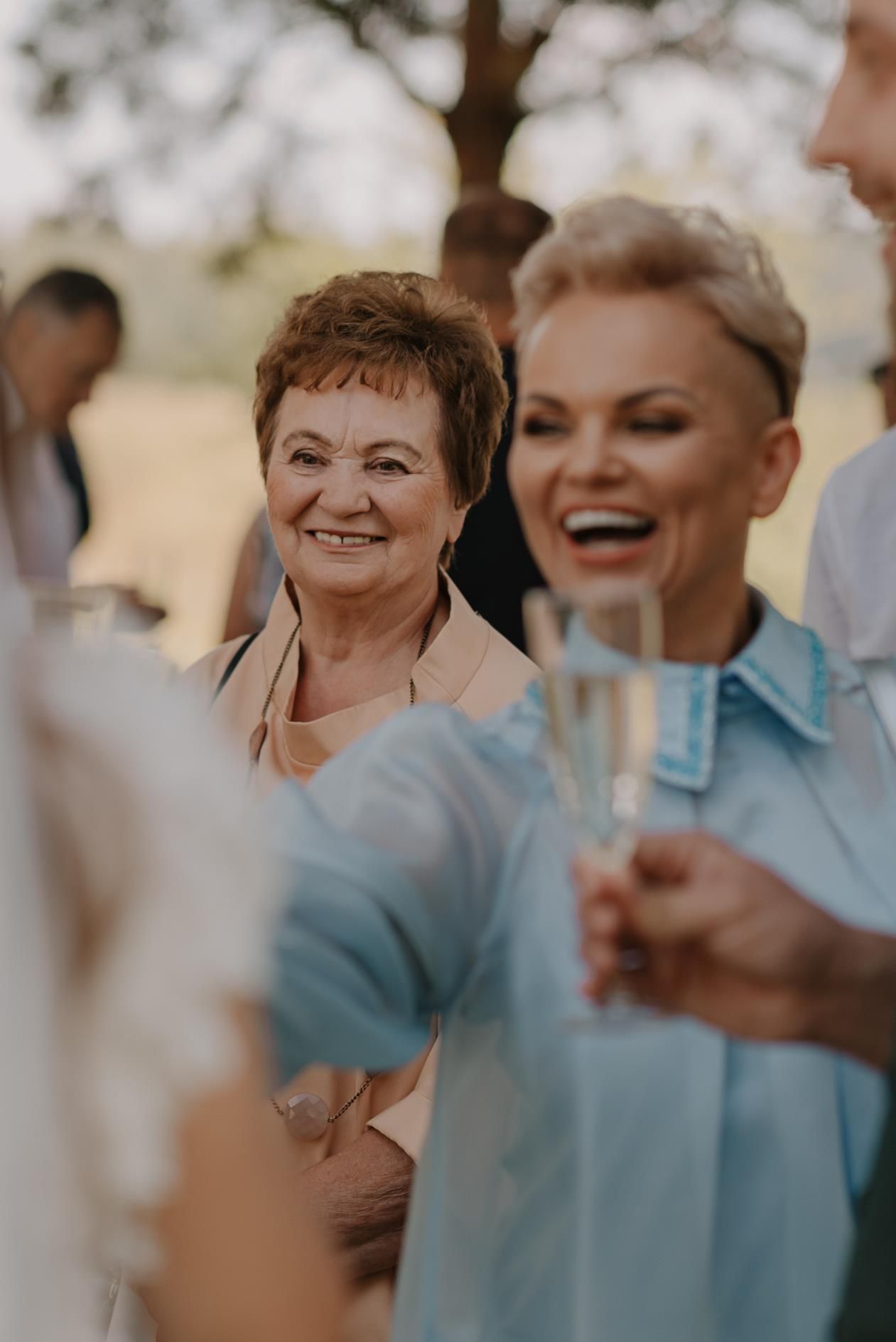 Wedding guests sharing joyful laughter during outdoor celebration.