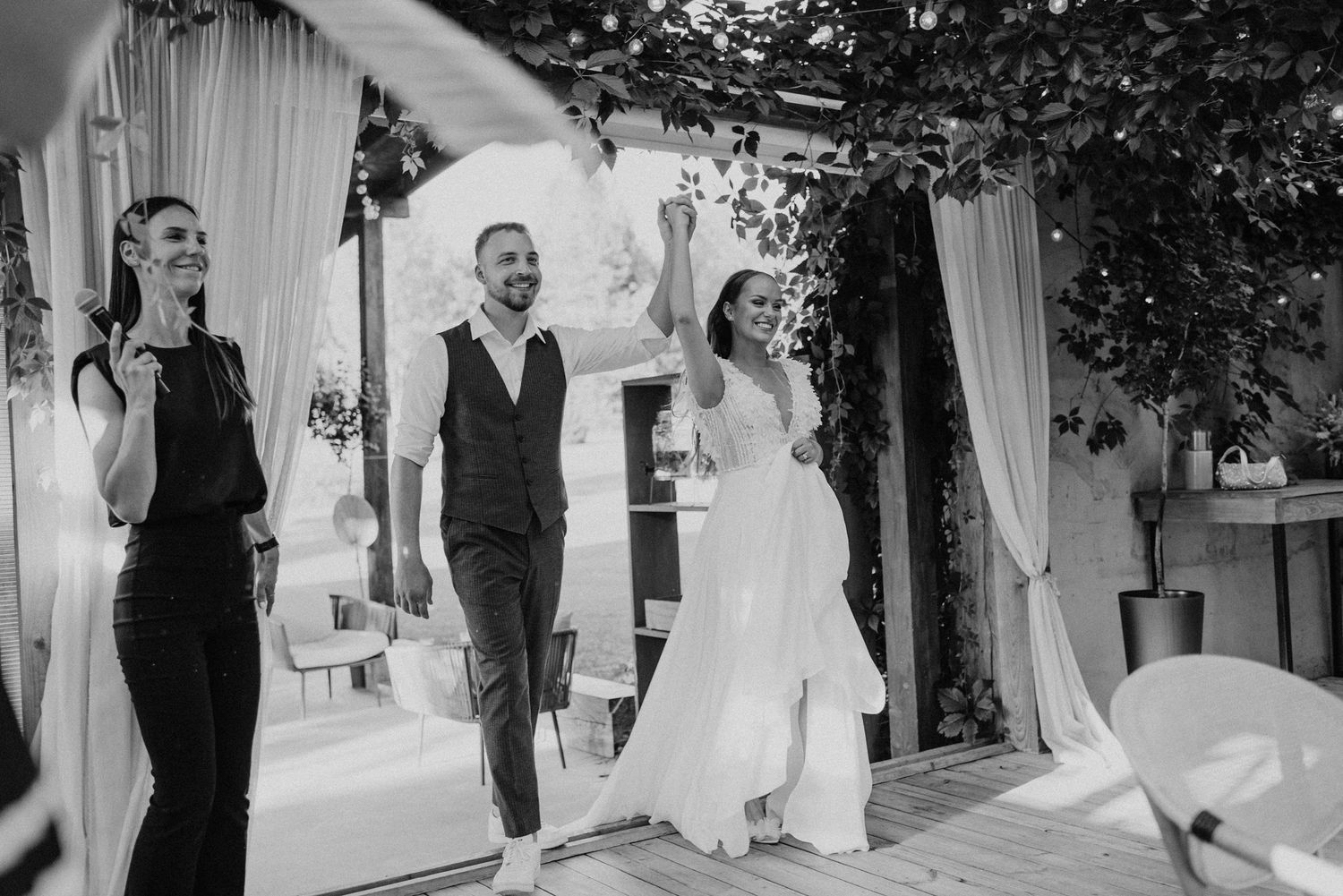 Joyful celebration during an outdoor wedding ceremony under a white draped archway.