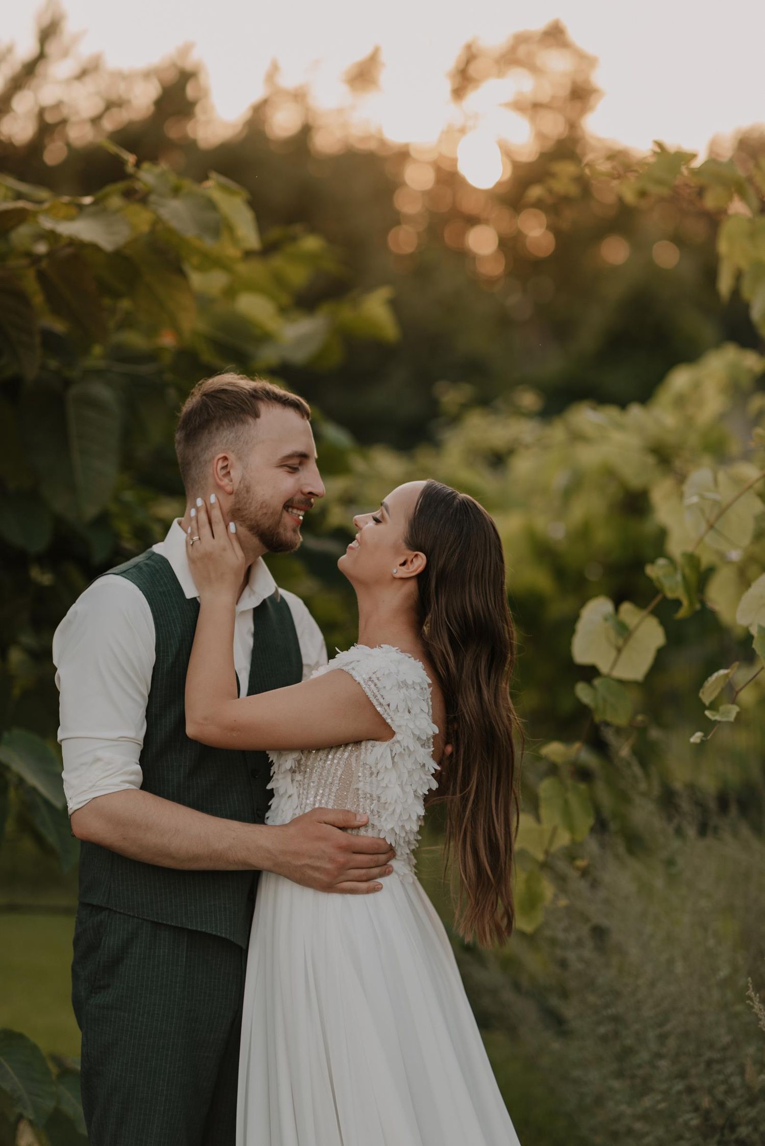 Romantic couple embracing in a vineyard during golden hour sunset.