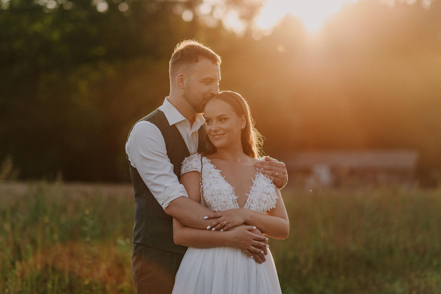 Intimate wedding portrait in a field during warm sunset light.