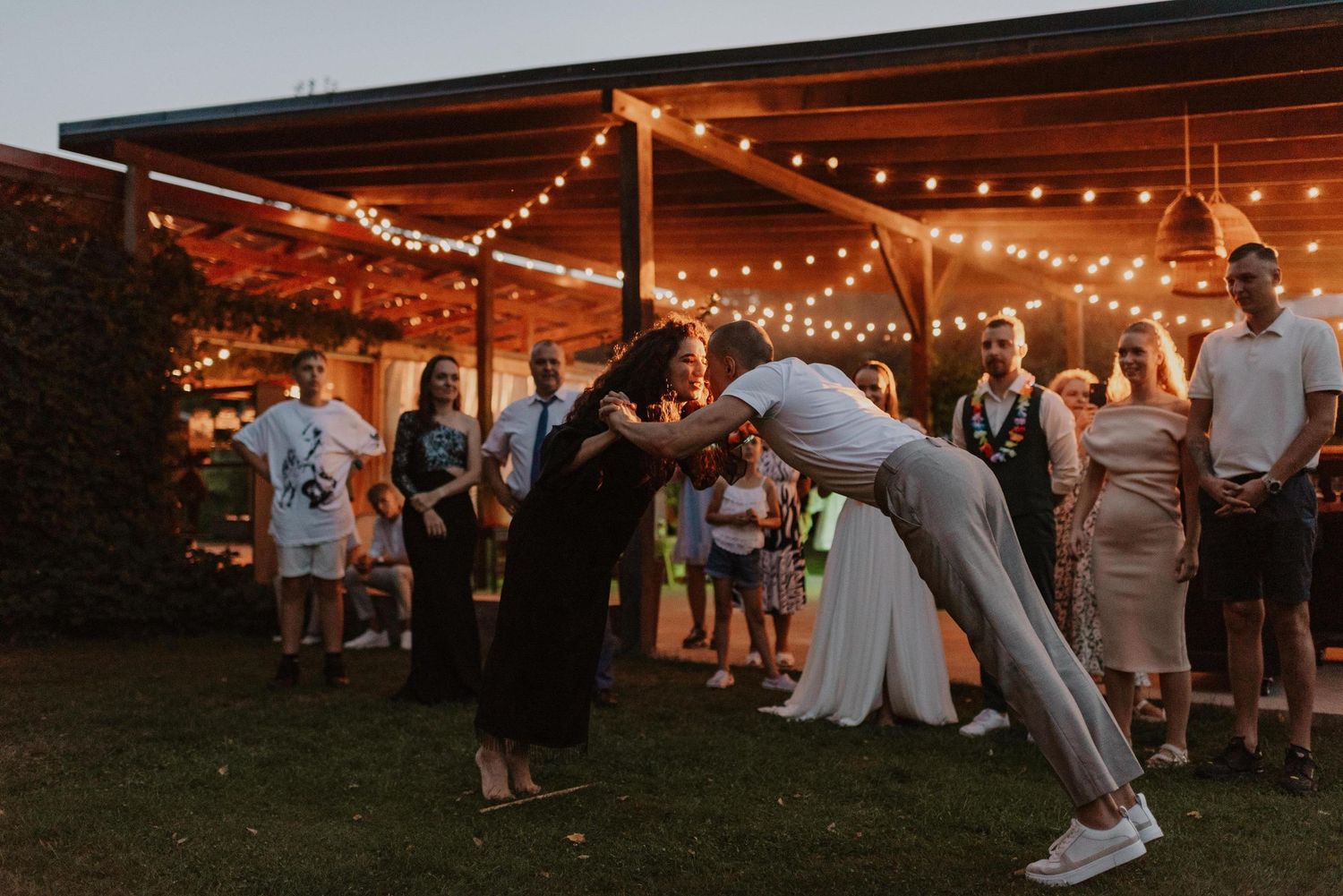Wedding reception celebration under string lights with a dramatic dip dance move.