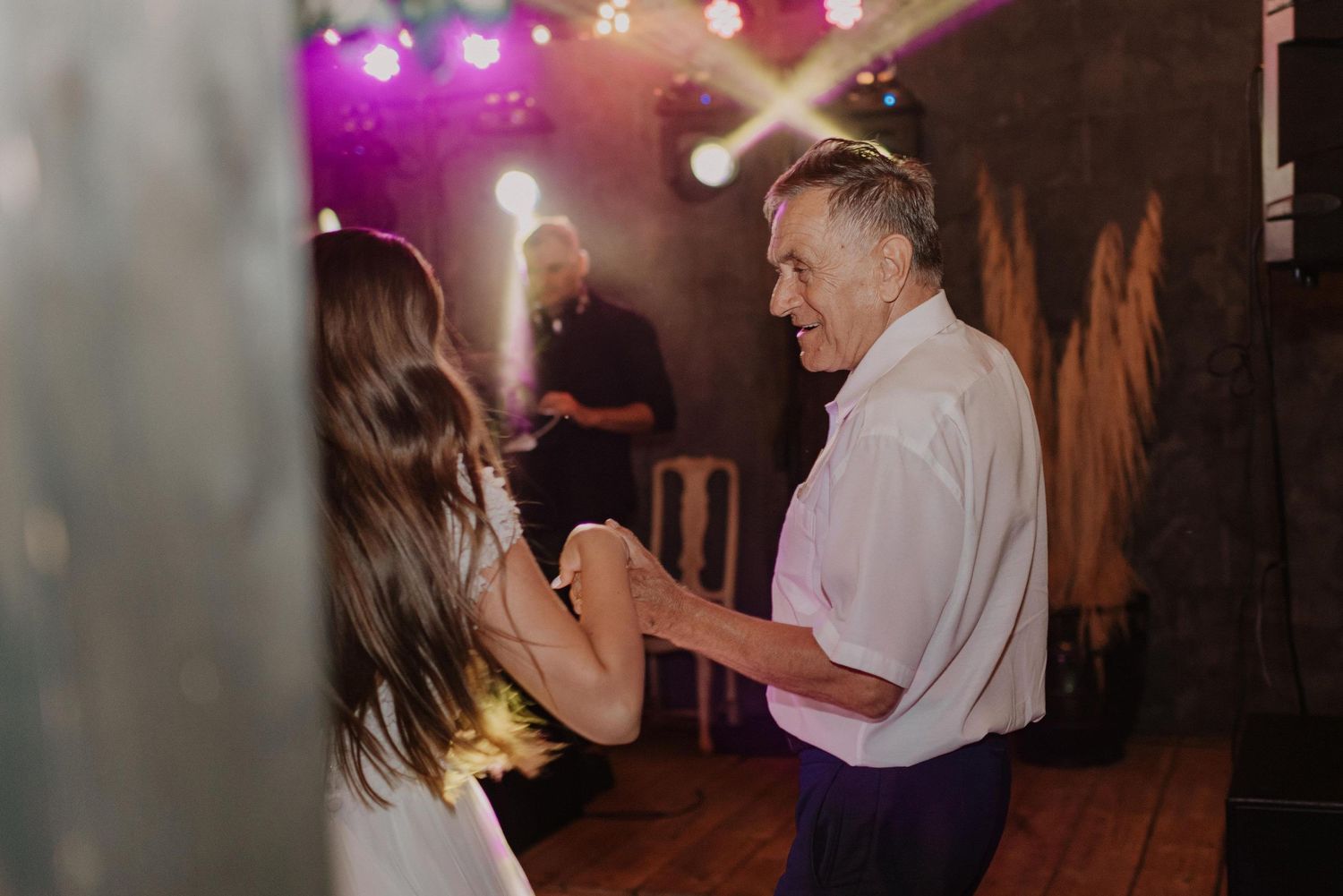Couple slow dancing in an intimate setting with purple mood lighting.