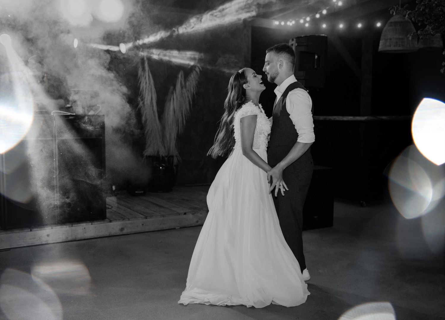 A couple shares a romantic dance under twinkling lights at their wedding reception.