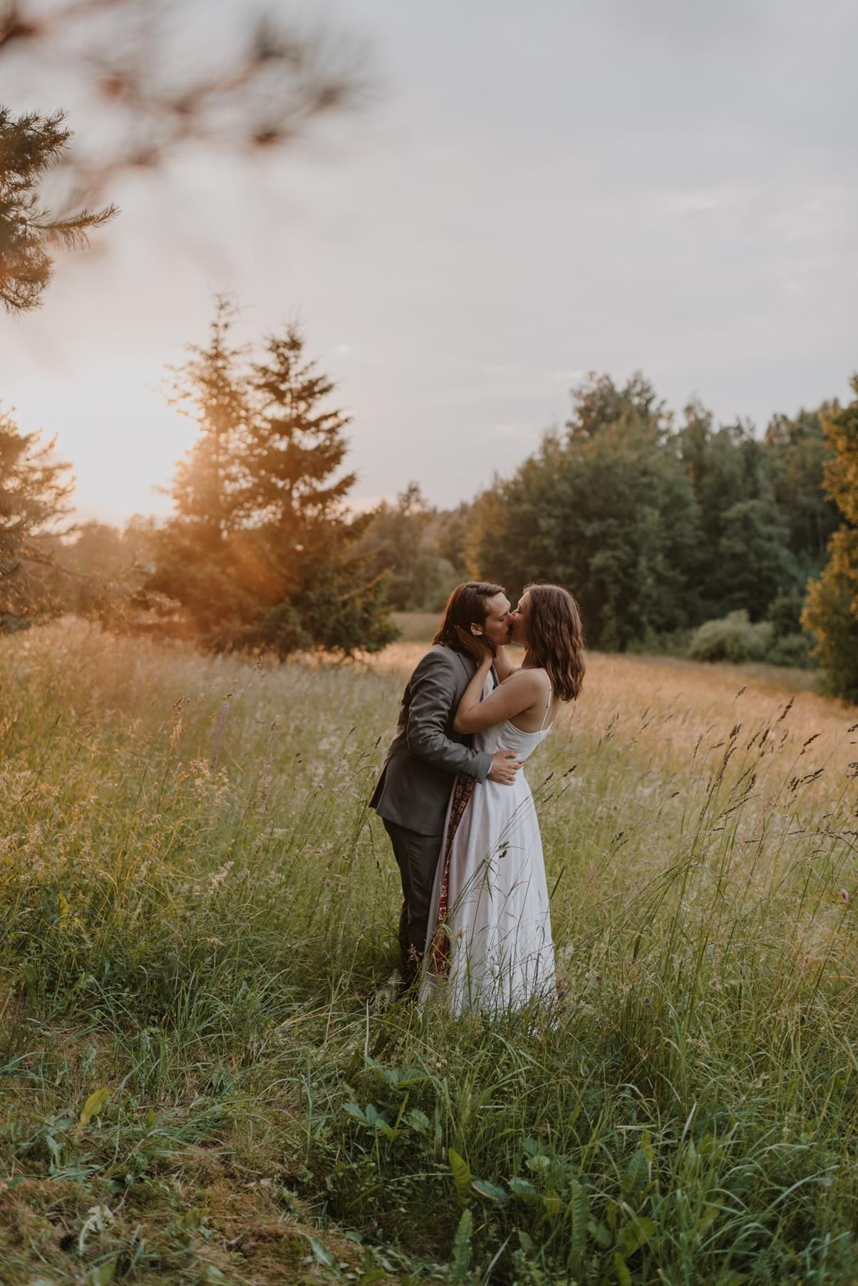 Romantic couple embracing in sunlit meadow during golden hour.