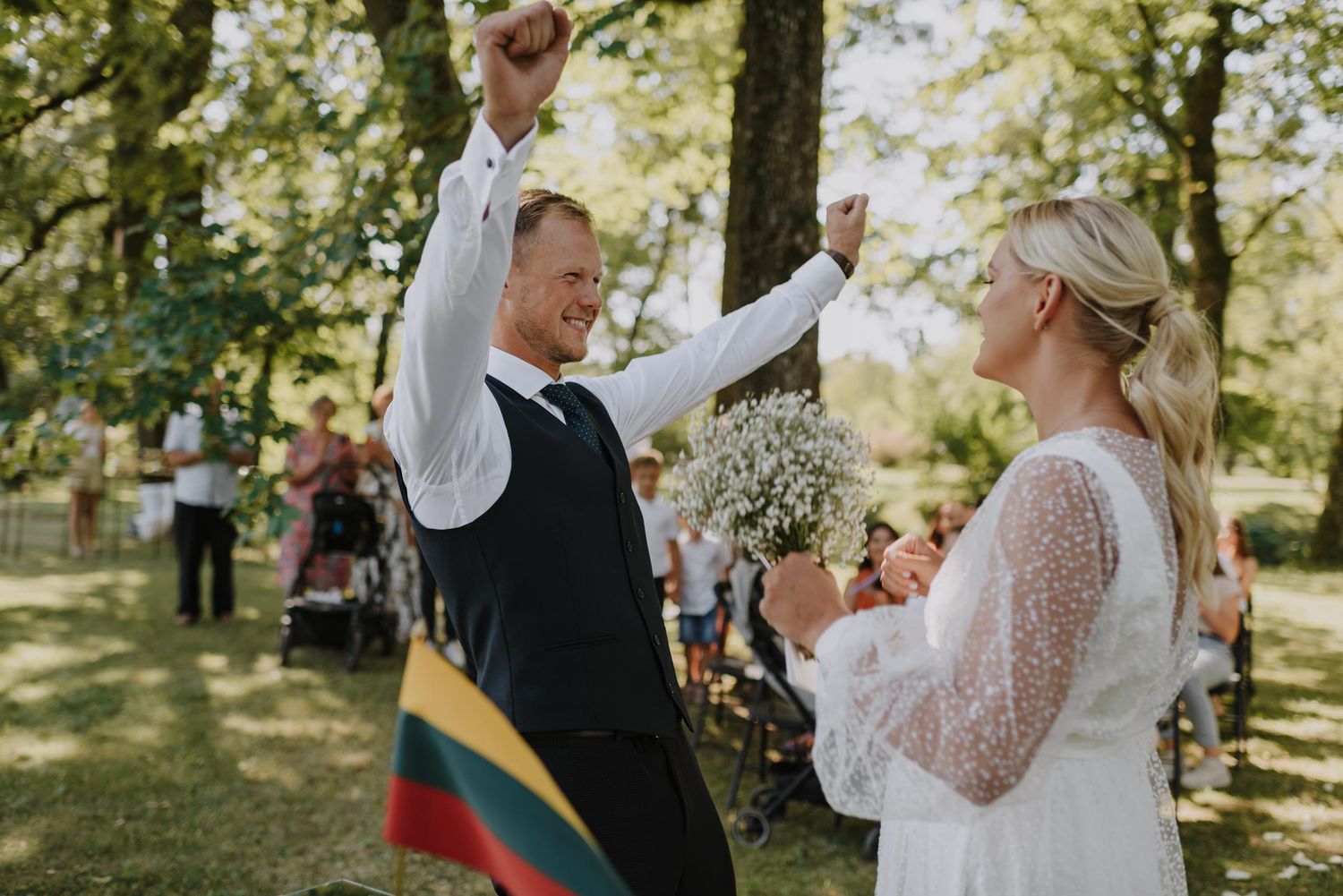 Wedding ceremony moment outdoors with couple and guests under trees.