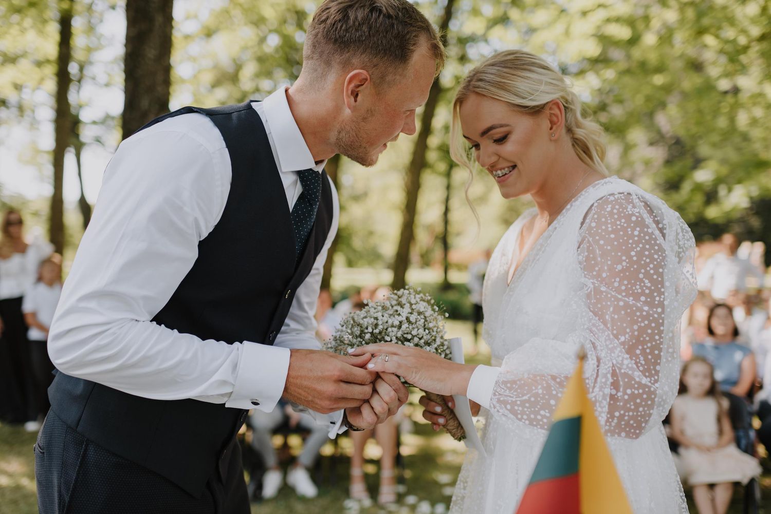 Couple dancing together at outdoor wedding celebration with guests in background.