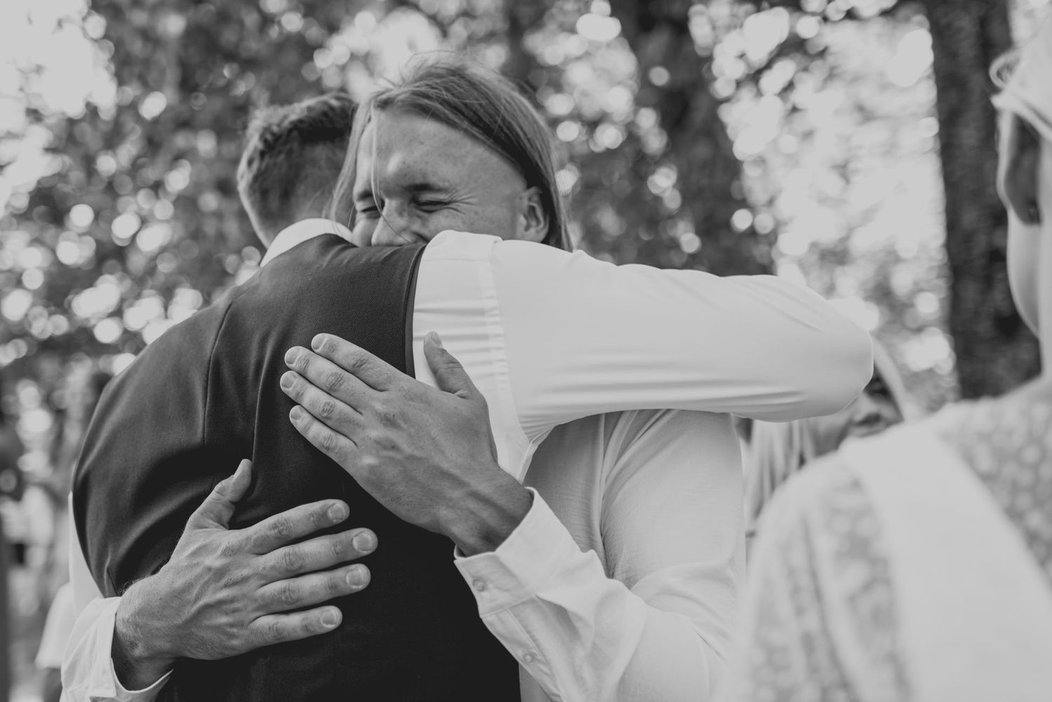 Black and white photo of couple dancing together at outdoor wedding.