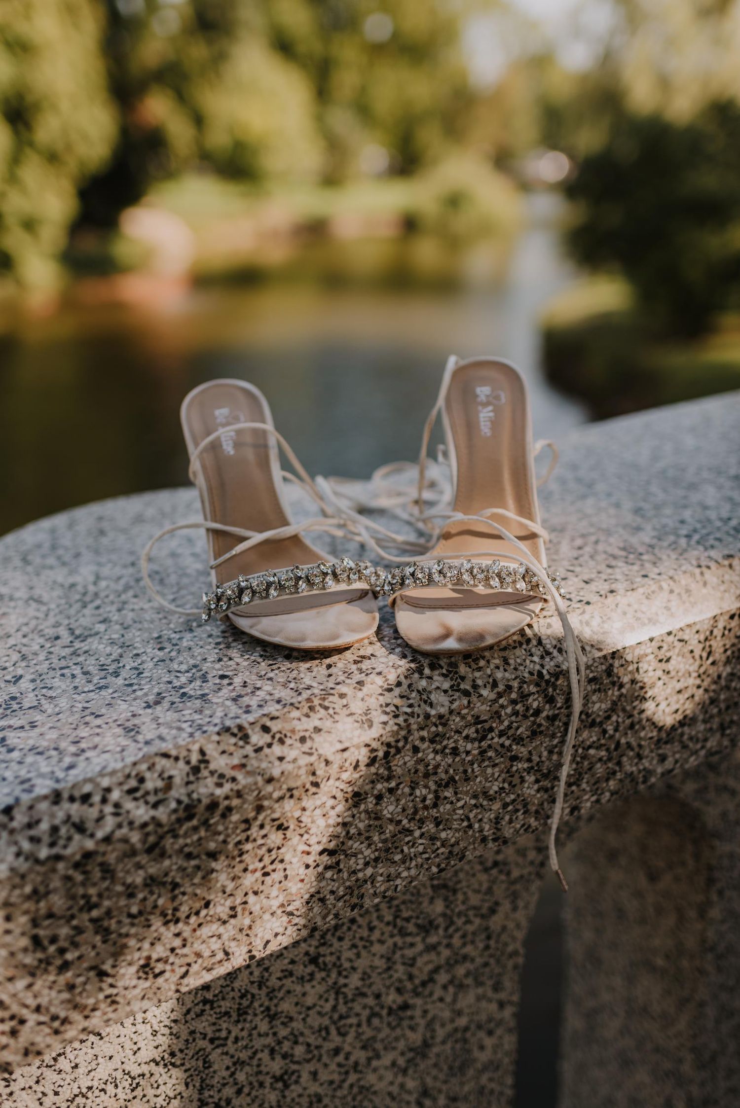 Elegant bridal shoes displayed on stone surface in natural lighting.