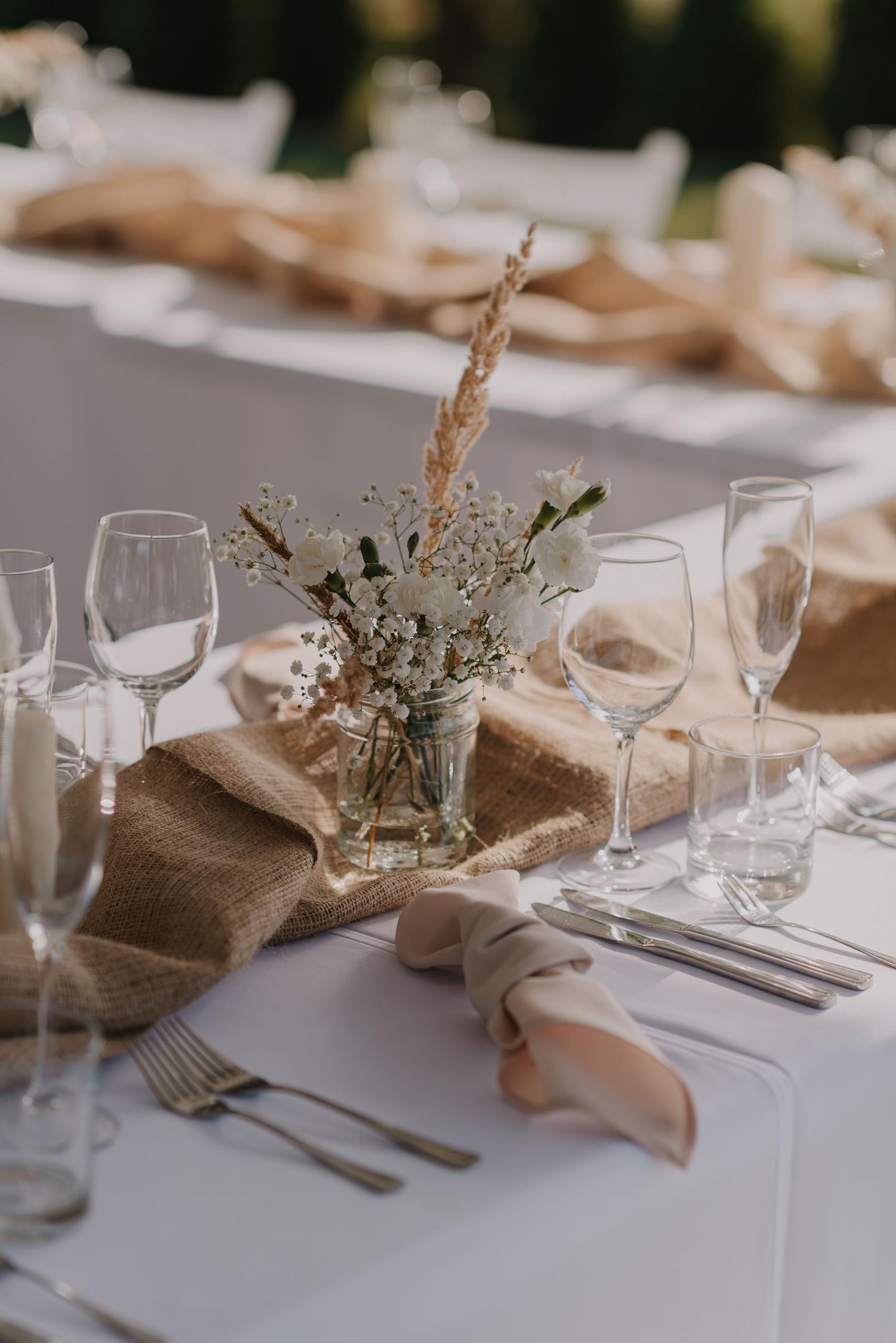 Elegant wedding table setting with rustic burlap runners and dried flower arrangements.