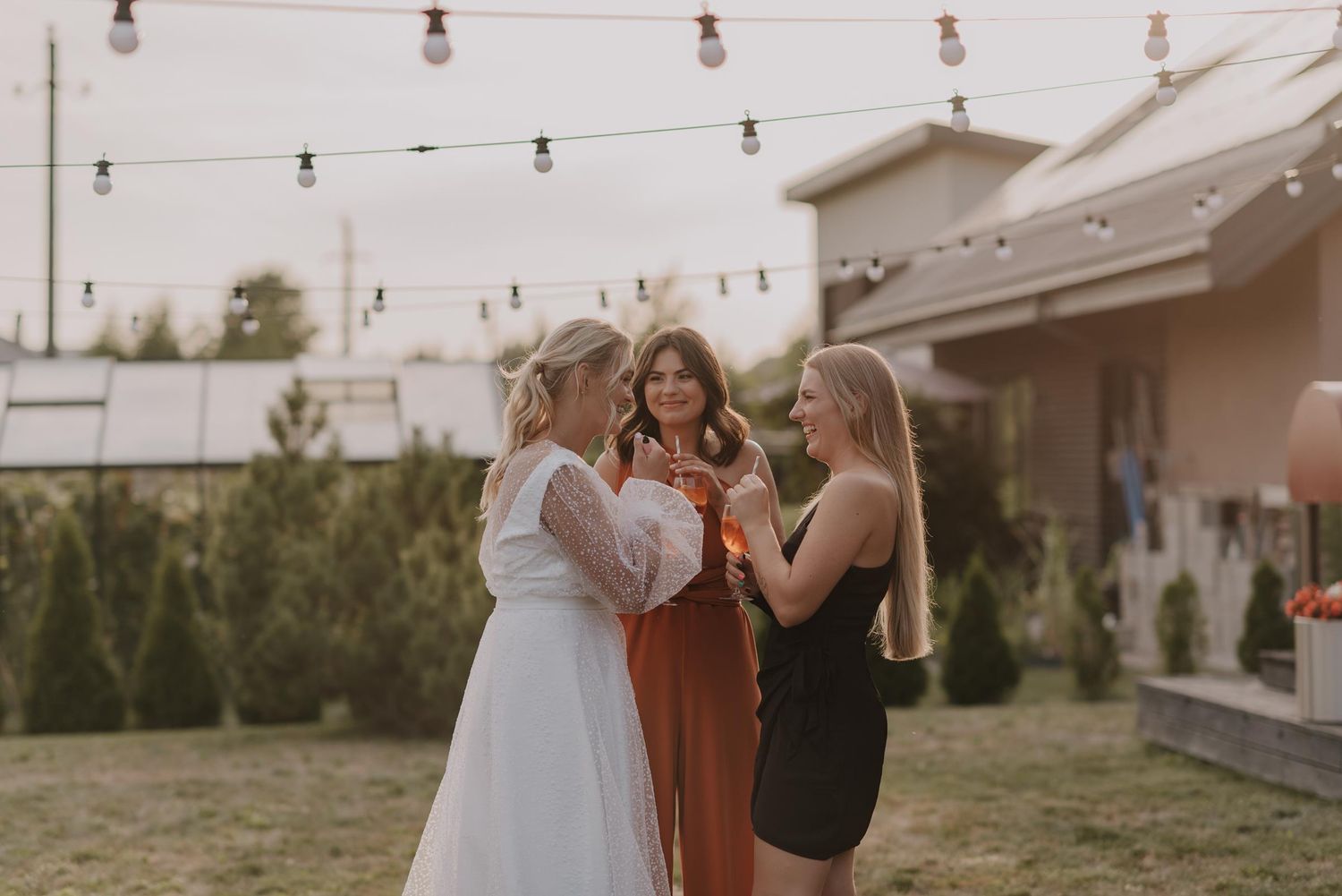 Outdoor wedding venue decorated with string lights and white chairs.