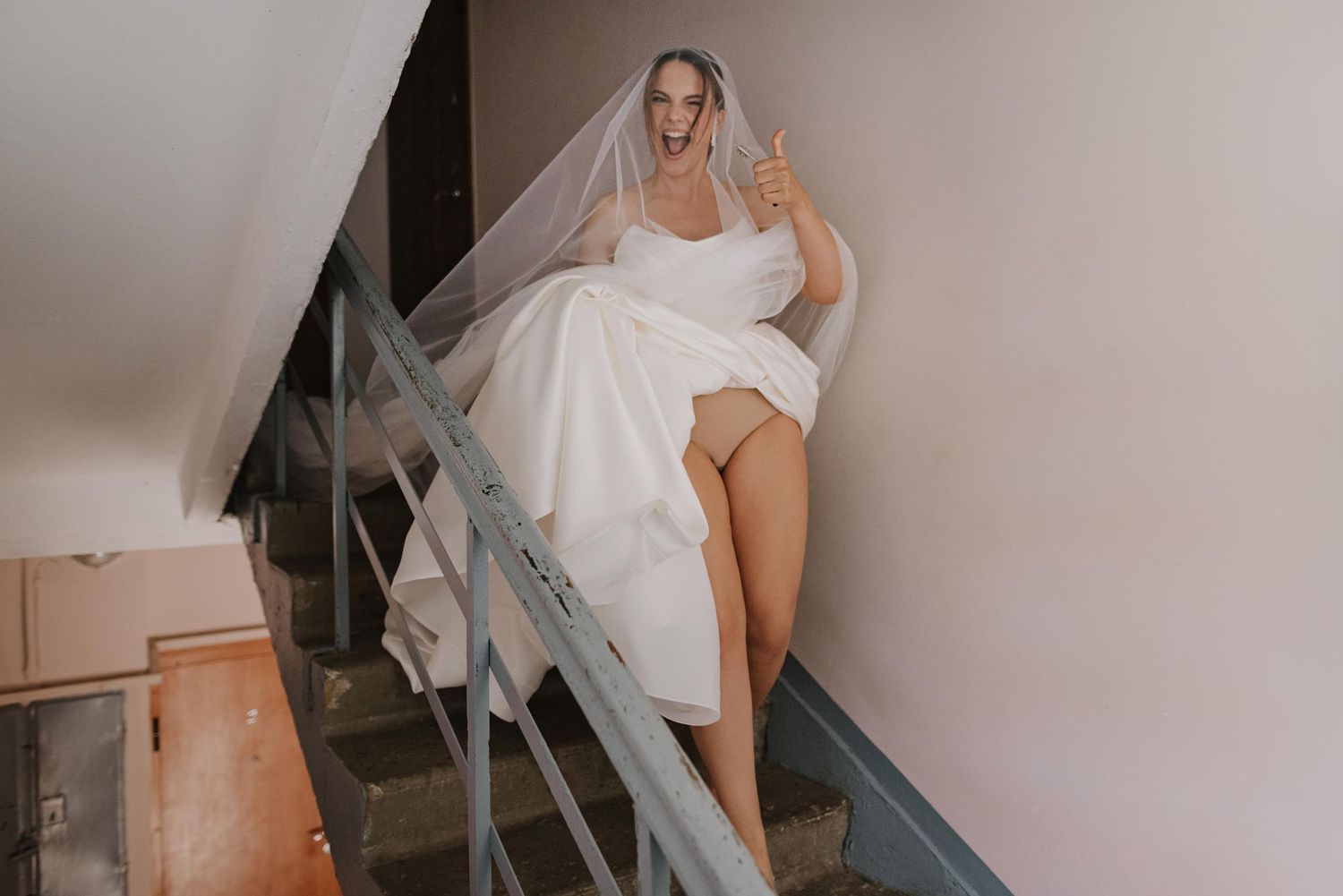 Bride in white wedding dress getting ready in a sunlit room.