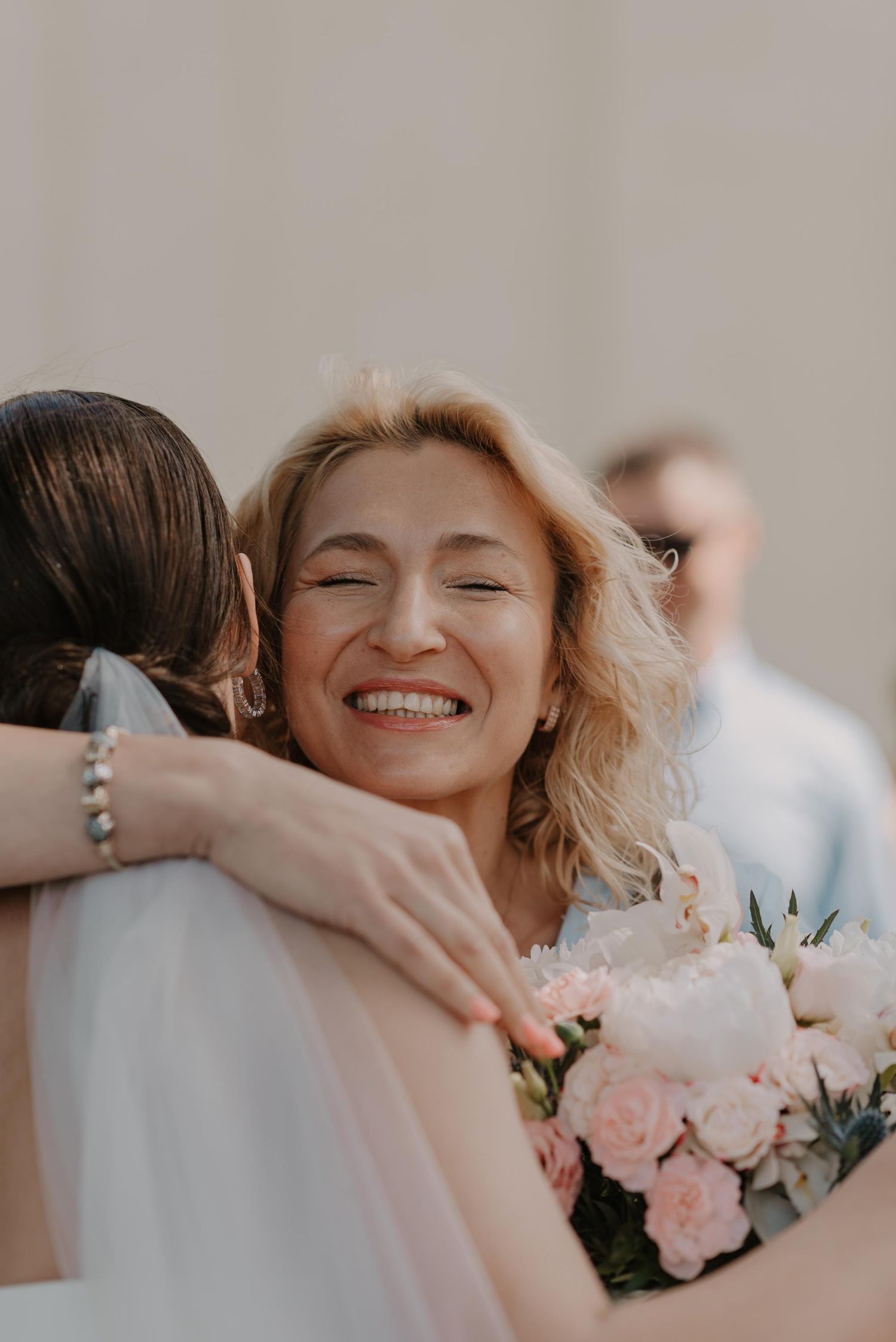 Joyful wedding celebration with pink roses and embraces among attendees.