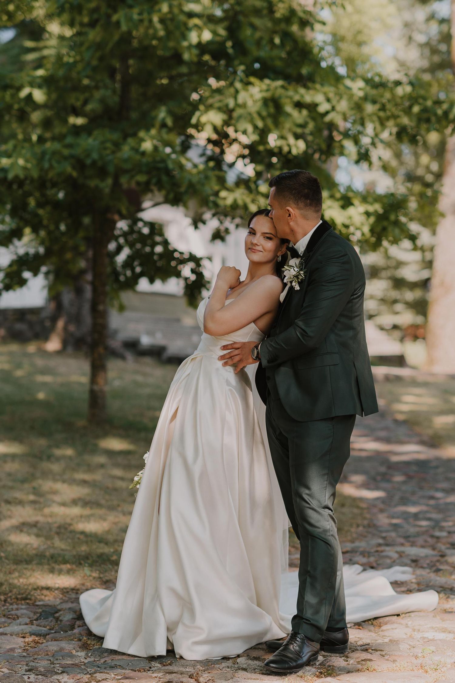 A couple shares their first dance outdoors surrounded by lush greenery and trees.