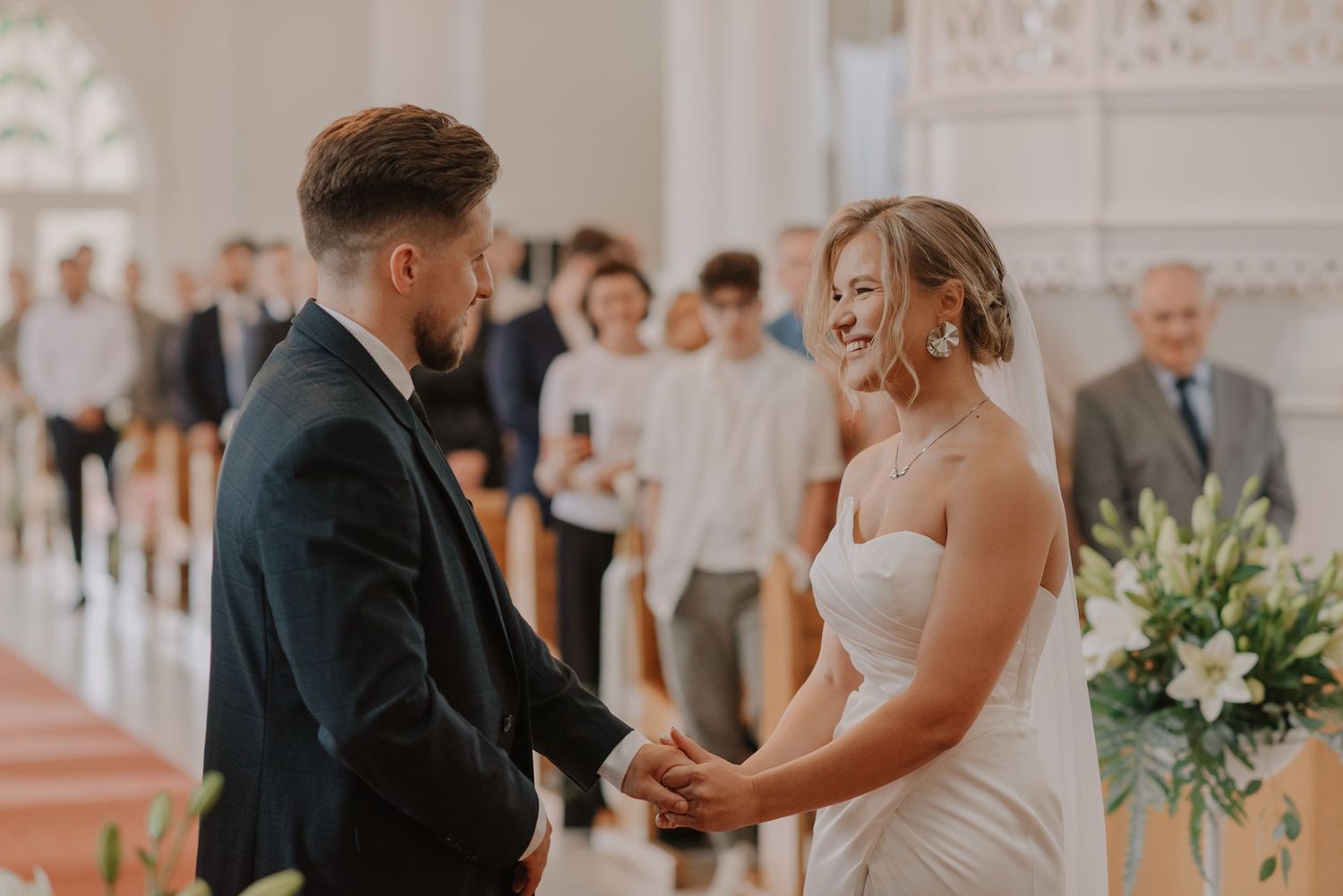 A tender moment between a couple during their wedding ceremony with elegant white decor.