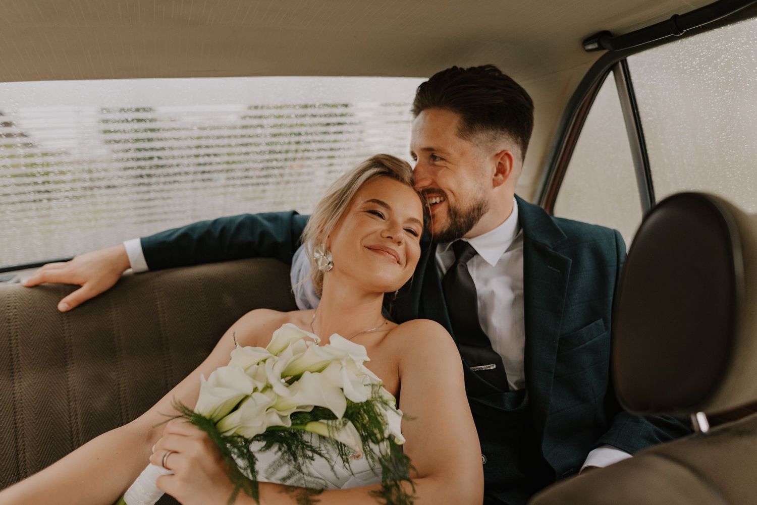 A happy couple shares intimate moments in the backseat of a classic car.