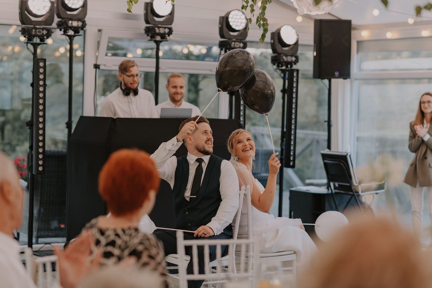 Wedding guests react with joy during a reception with professional lighting setup.