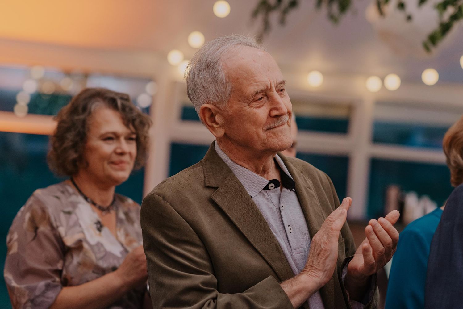 Elderly guests applaud during an emotional wedding reception moment.