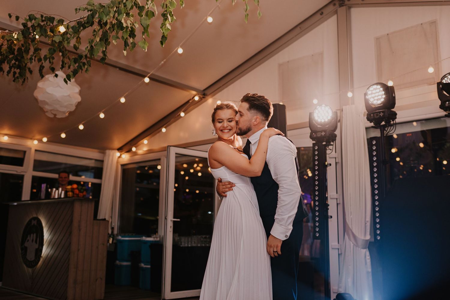 Elegant wedding celebration with twinkle lights and white decor in an indoor venue.