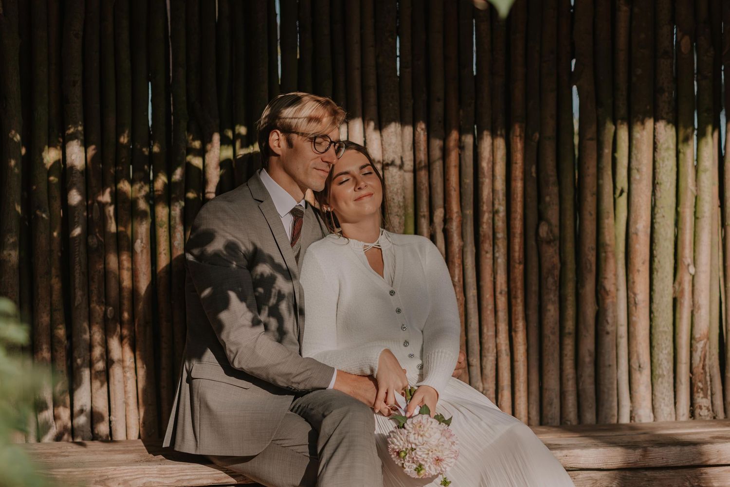 A tender wedding scene unfolds against a rustic wooden fence backdrop.