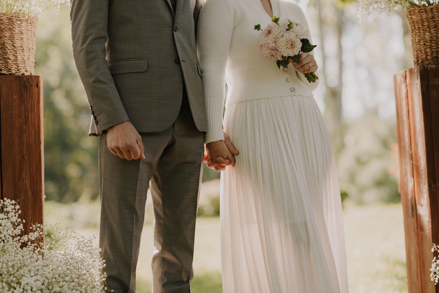 Natural light illuminates a romantic garden wedding scene with rustic wooden post decorations.