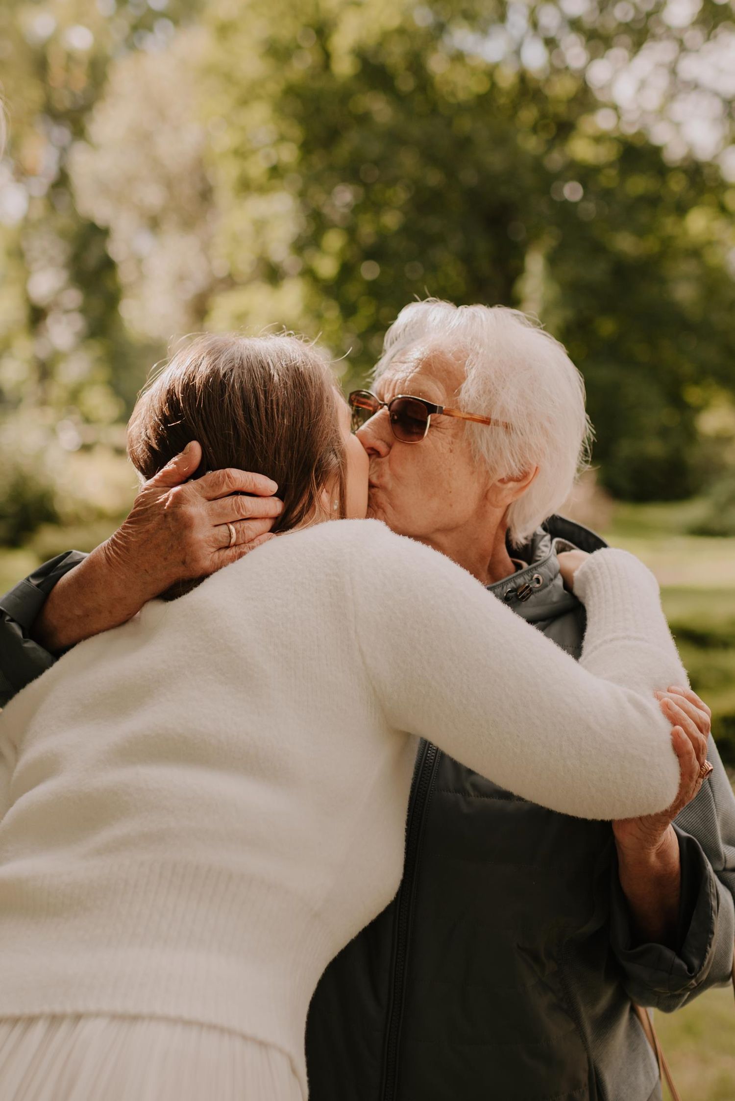 Heartfelt embrace between family members at outdoor wedding ceremony.