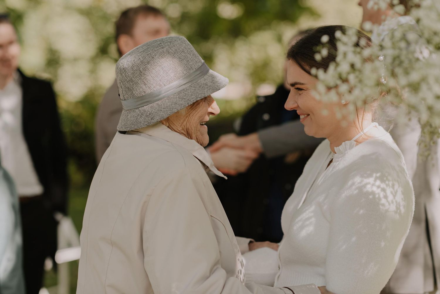 Family members sharing warm hugs during an outdoor wedding celebration.