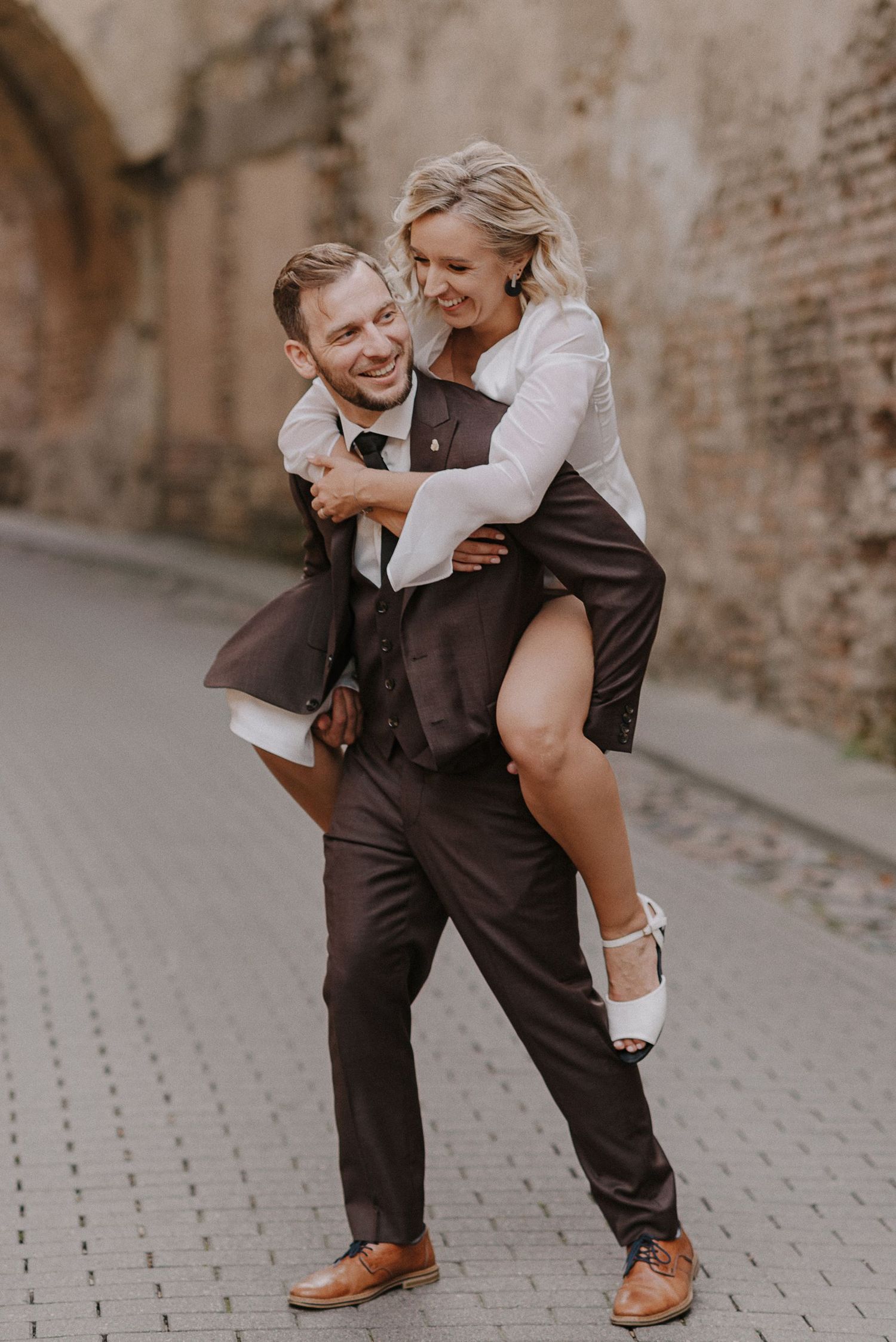 A playful wedding photoshoot on a cobblestone street with vintage architecture.