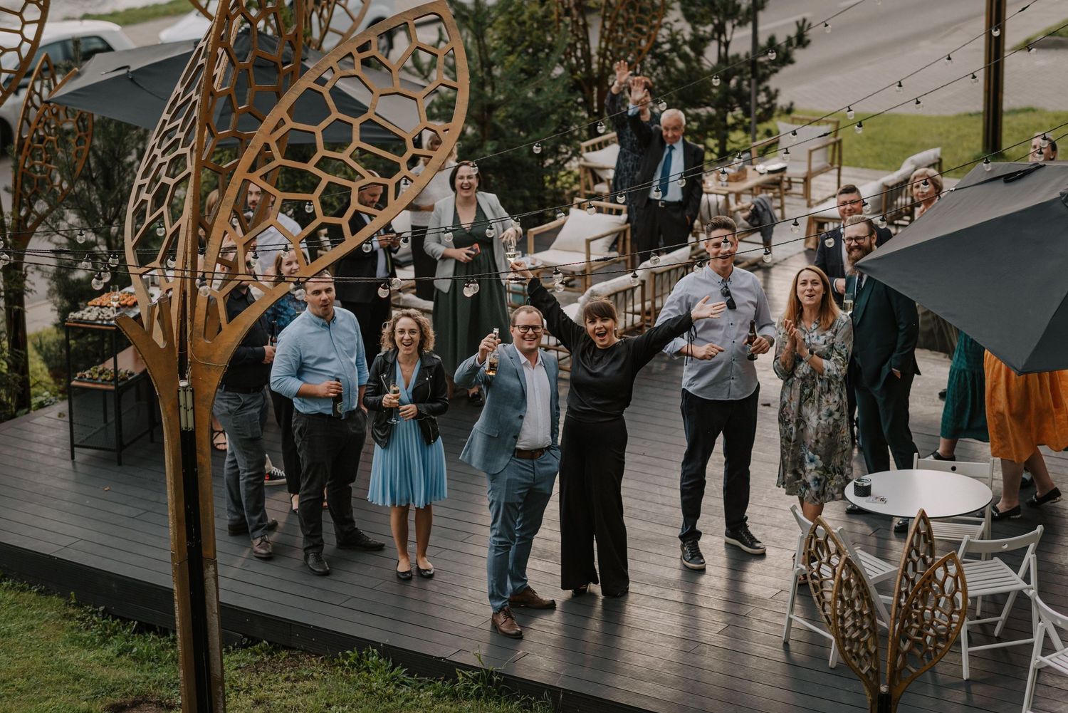 Wedding guests dancing and celebrating on an outdoor deck with rustic decor.