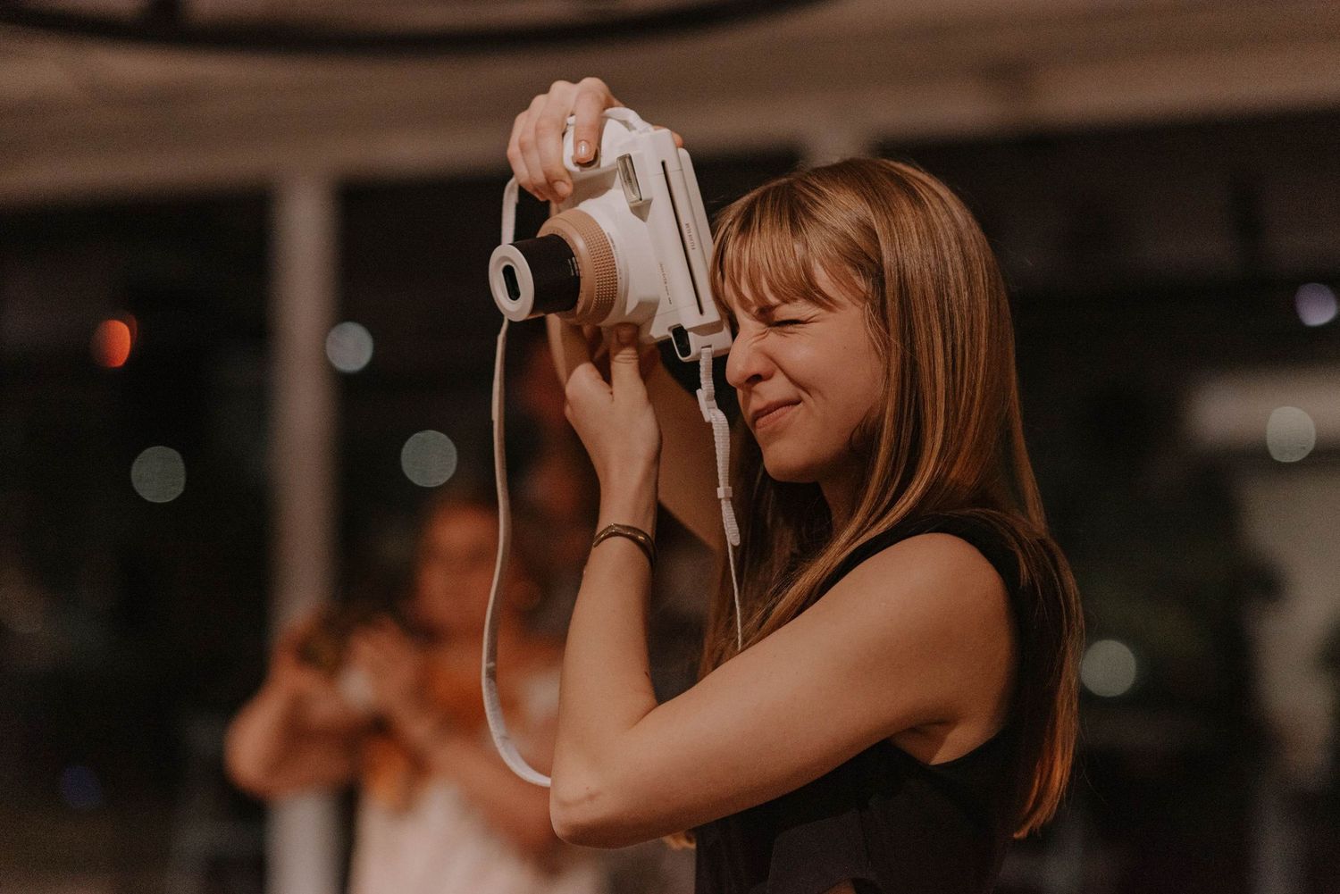 Woman enthusiastically taking photos with a vintage camera at an evening event.