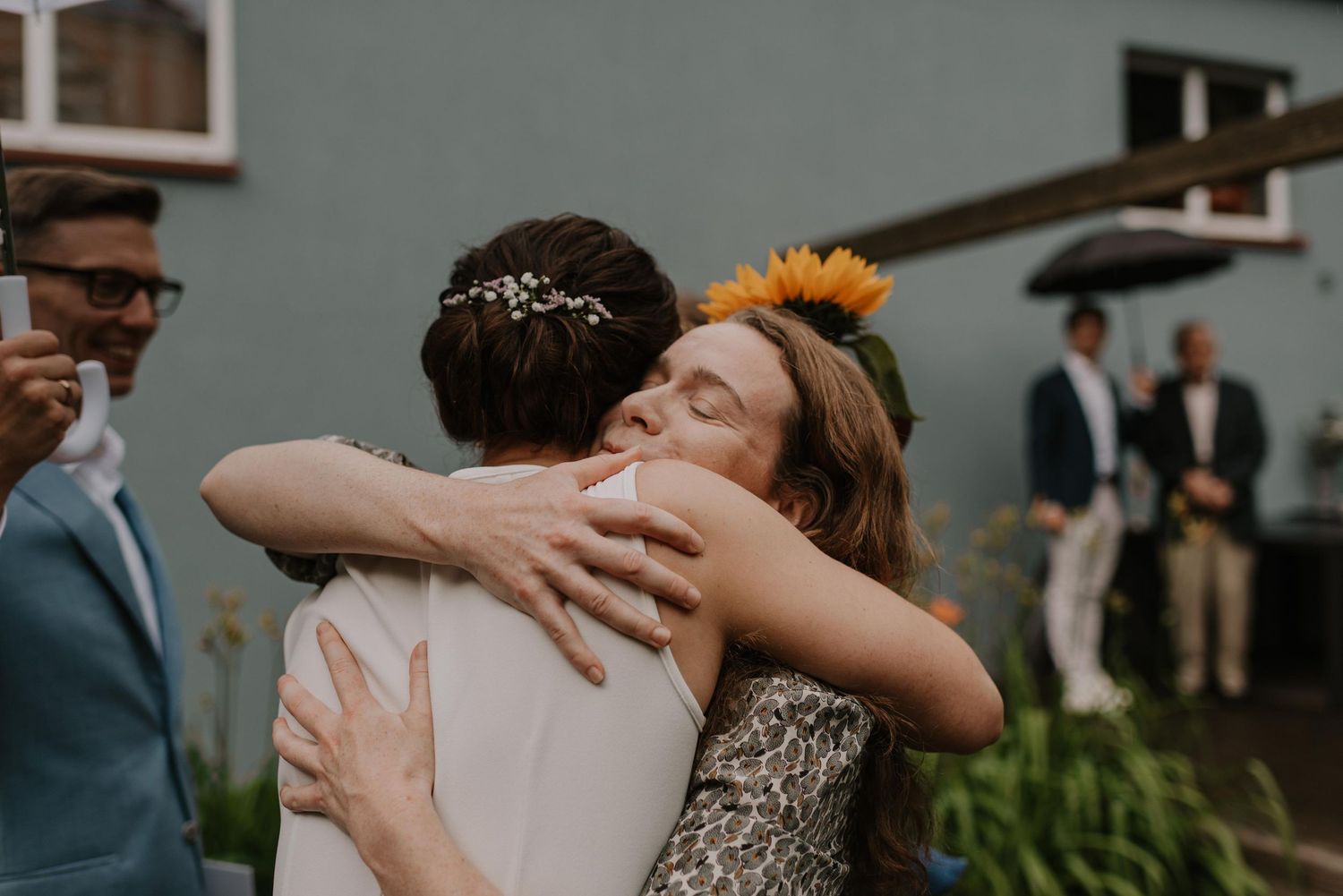 A couple shares an intimate embrace during their wedding ceremony set outdoors with rustic decor.