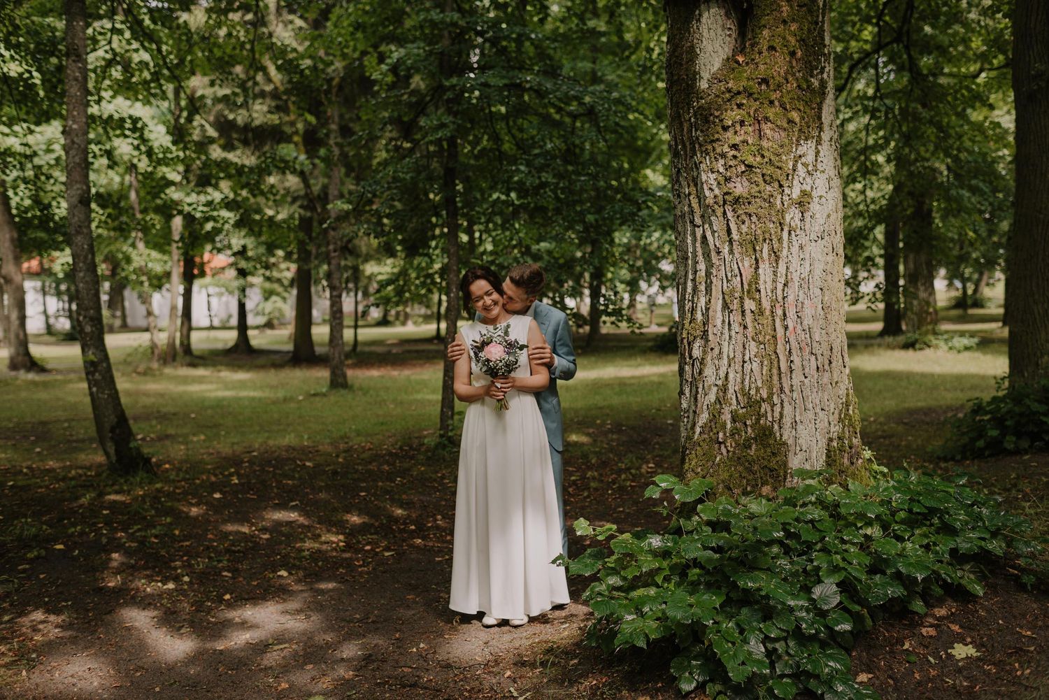 Romantic woodland wedding scene with natural lighting filtering through tall trees.