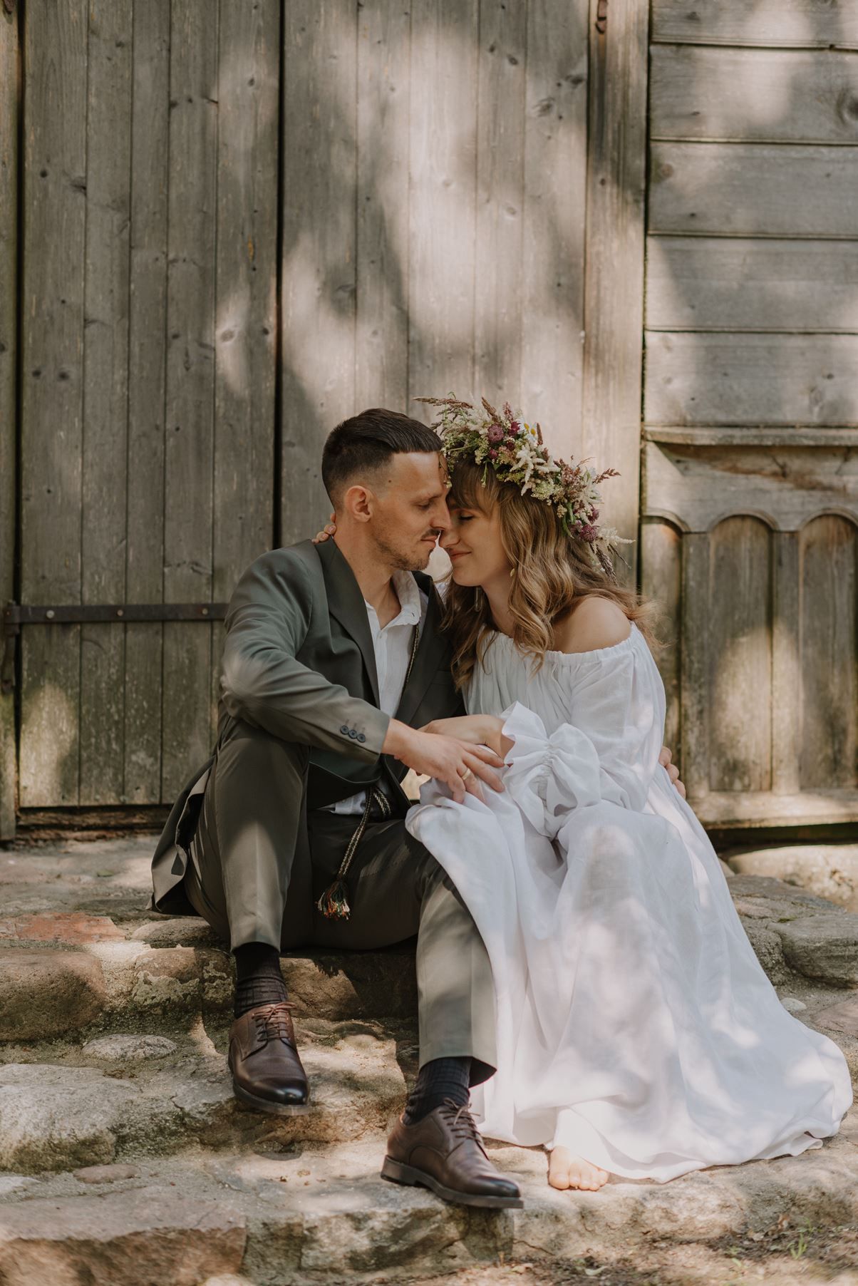 An intimate moment shared on wooden steps with dappled sunlight filtering through trees.
