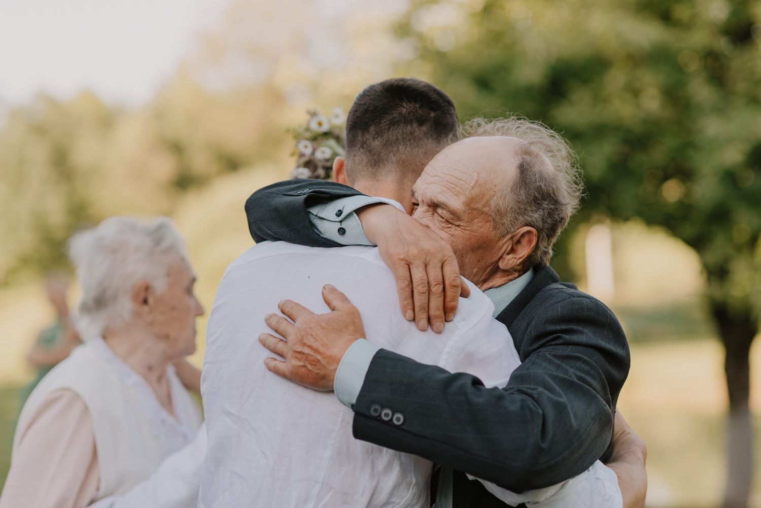 A heartfelt embrace captured during an outdoor celebration with golden sunlight.