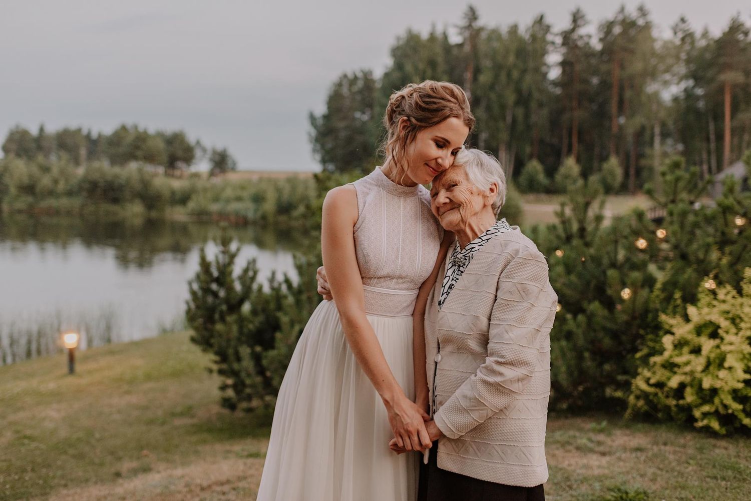 An emotional moment shared between a bride and an elderly relative at an outdoor venue.
