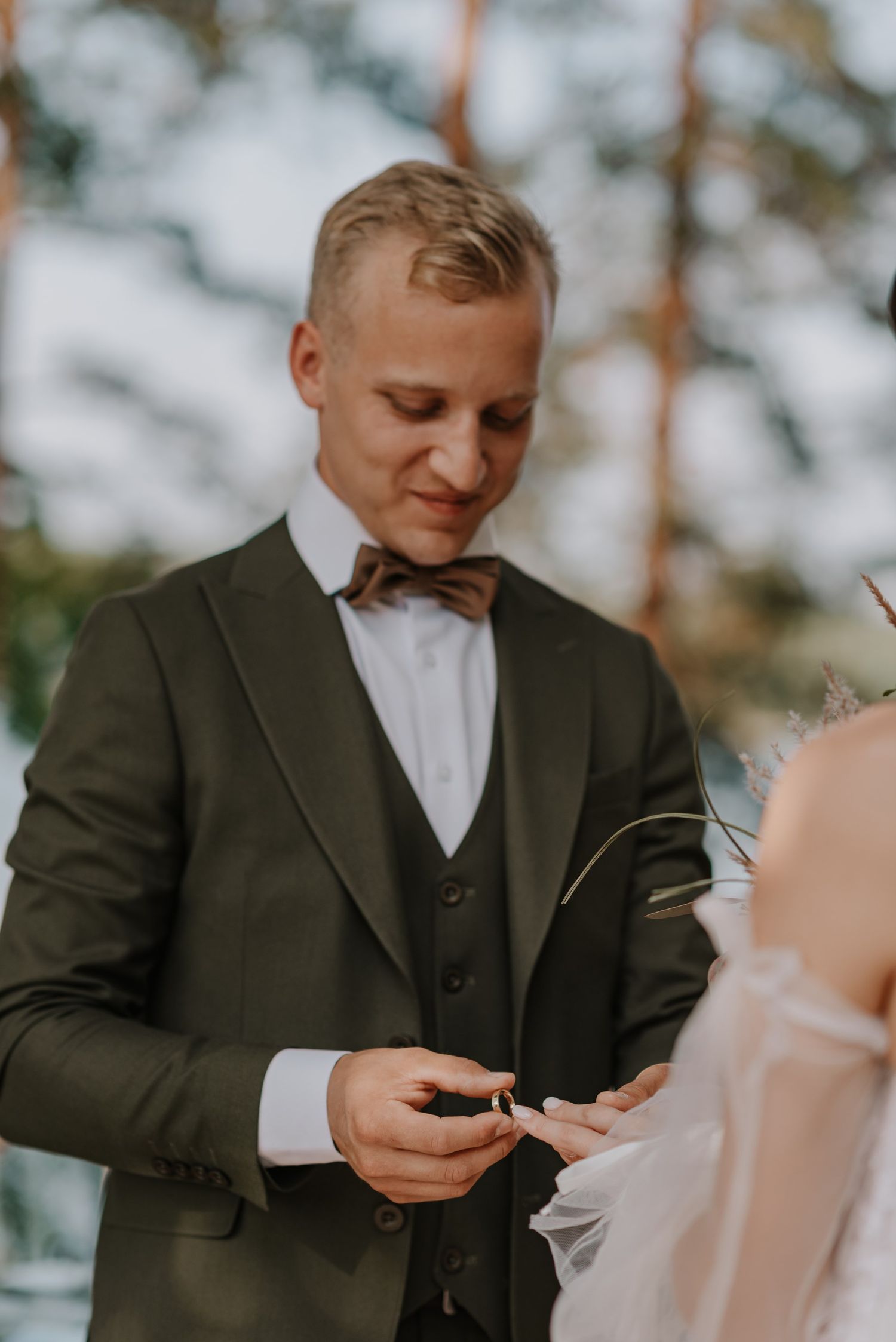 Groom in dark suit reads emotional vows during outdoor wedding ceremony.