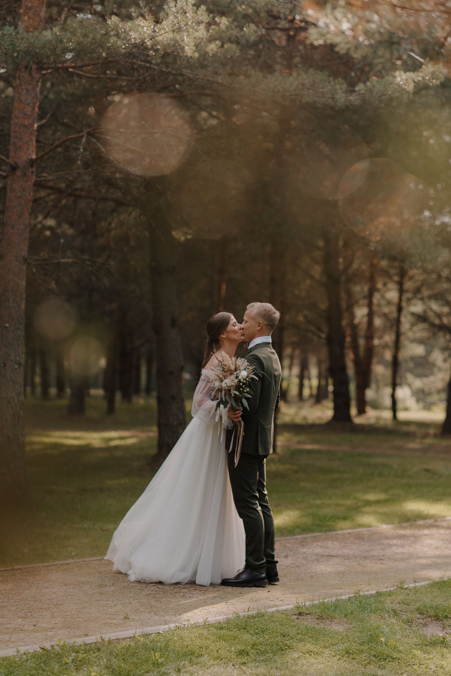 A romantic forest wedding photo with sunlight filtering through the trees.