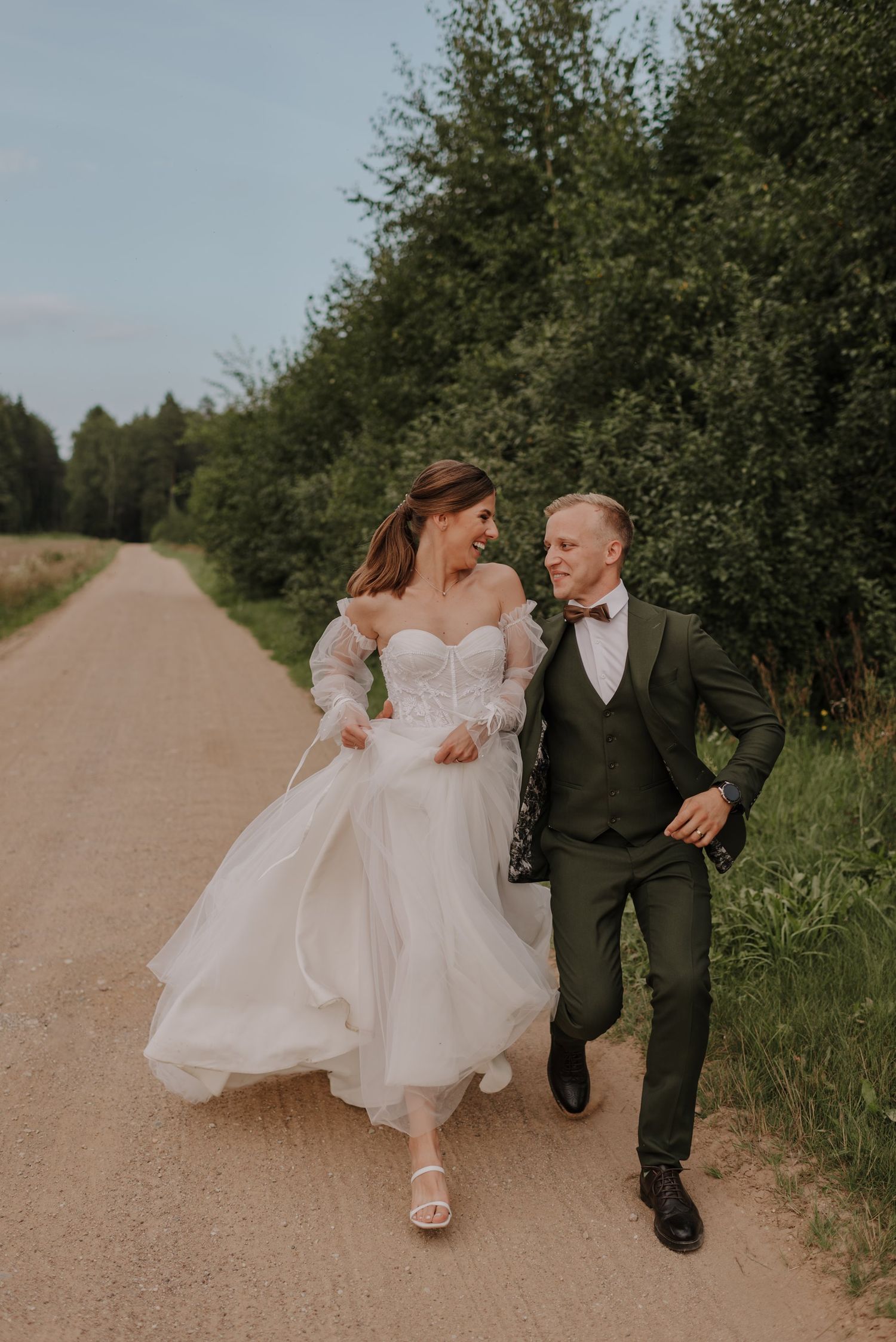 Couple walking together on a country path surrounded by lush greenery.