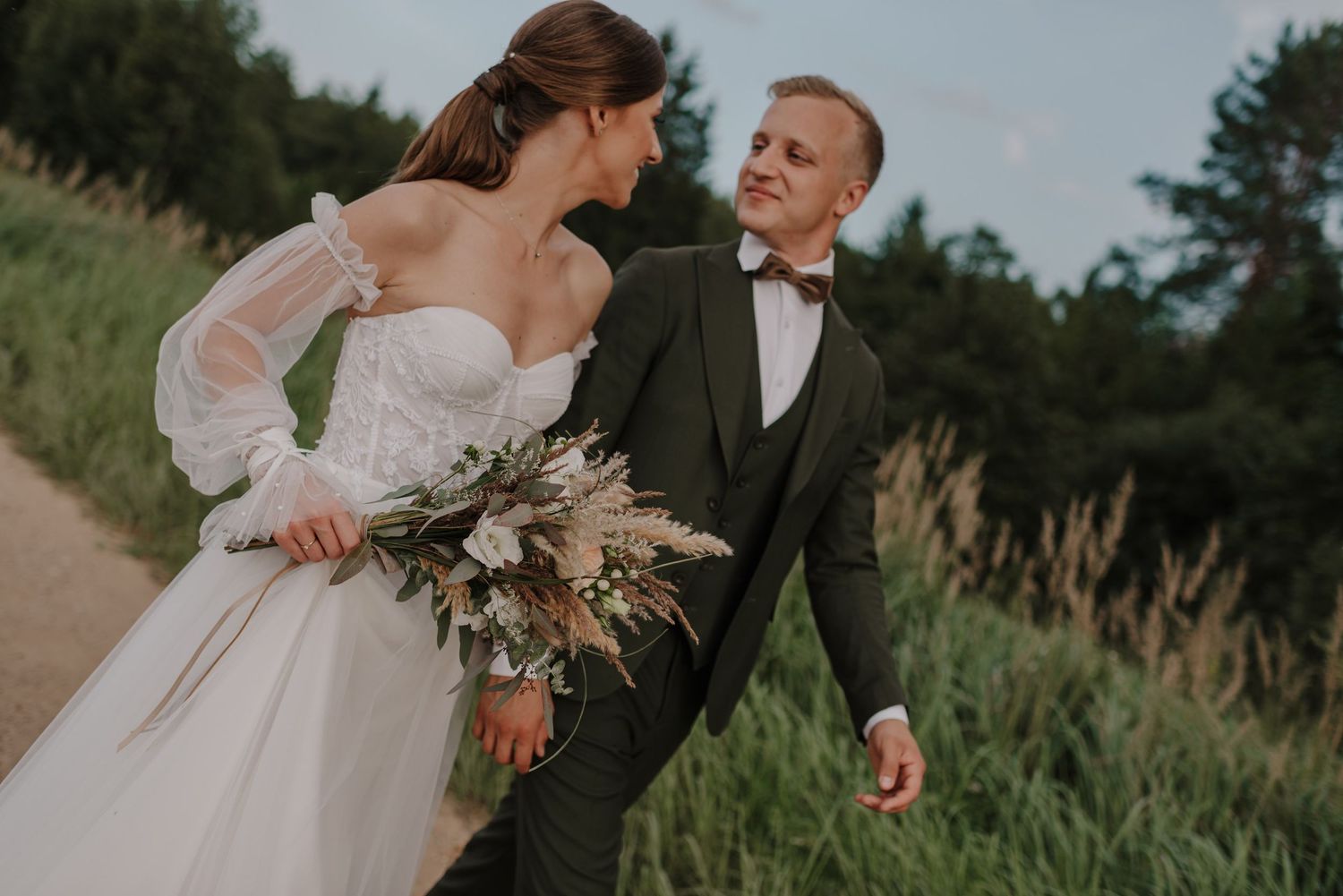 Romantic wedding portrait with couple sharing a moment among tall grass at sunset.