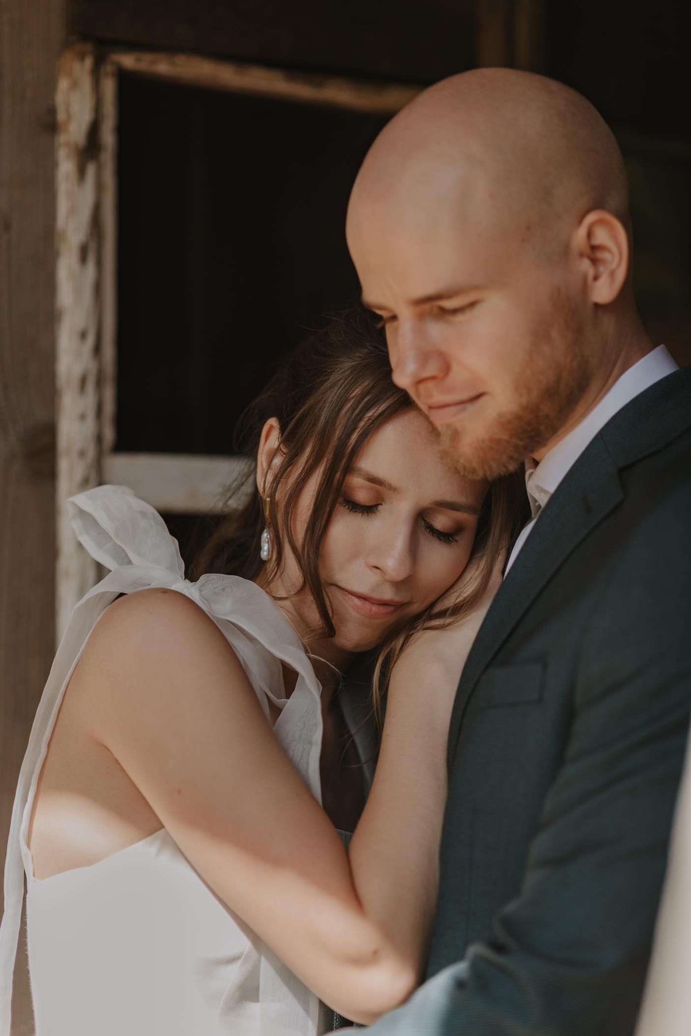 Intimate wedding couple portrait showing tender romantic moment in dark moody lighting.
