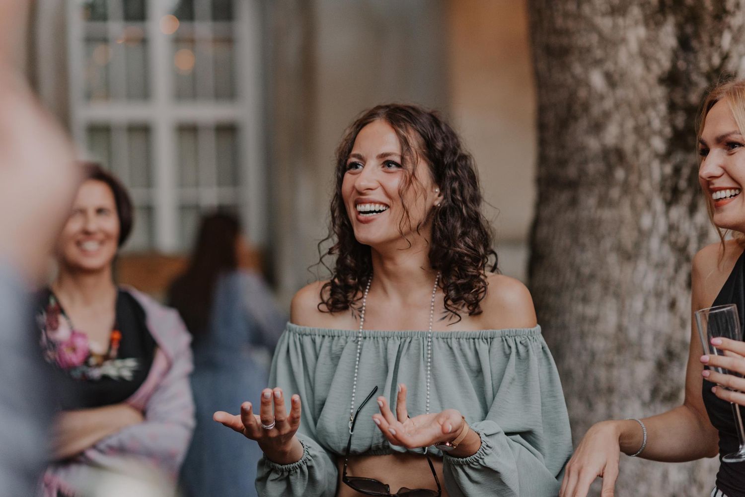 Wedding party members share laughter and dance together in an outdoor setting.