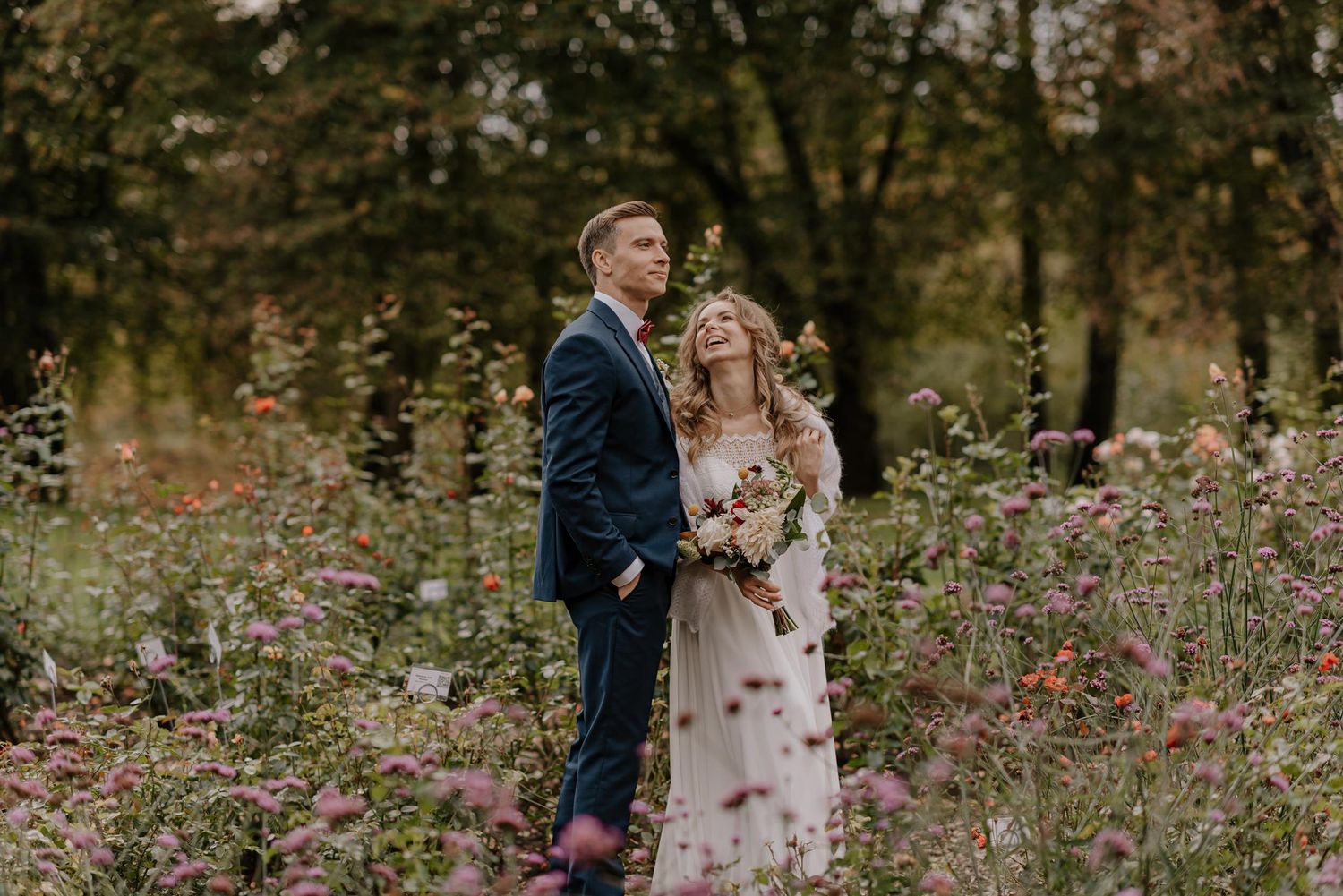 Couple embraces in field of wildflowers during autumn wedding photoshoot.