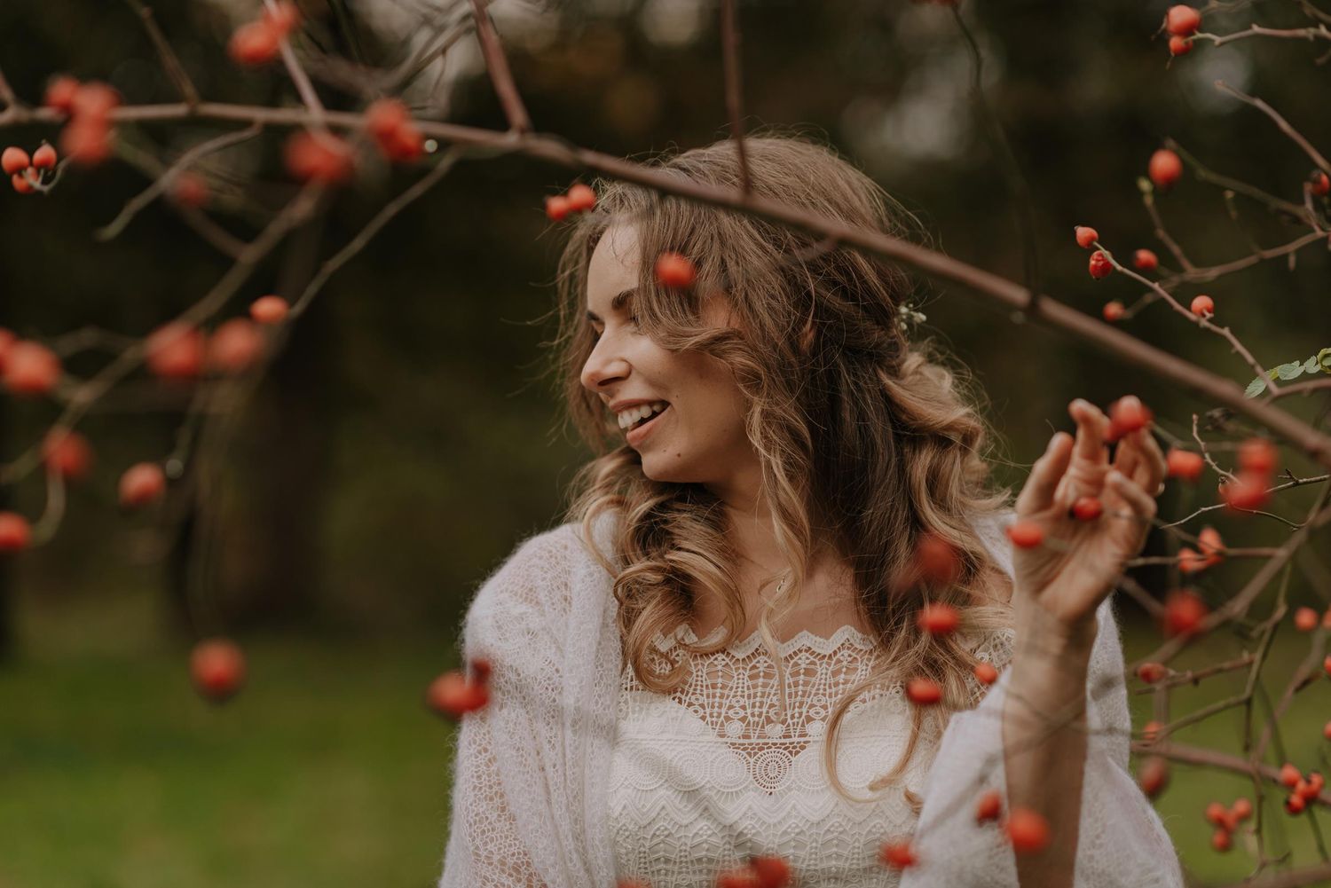 Romantic autumn wedding couple dancing together surrounded by vibrant red berries and fall foliage.